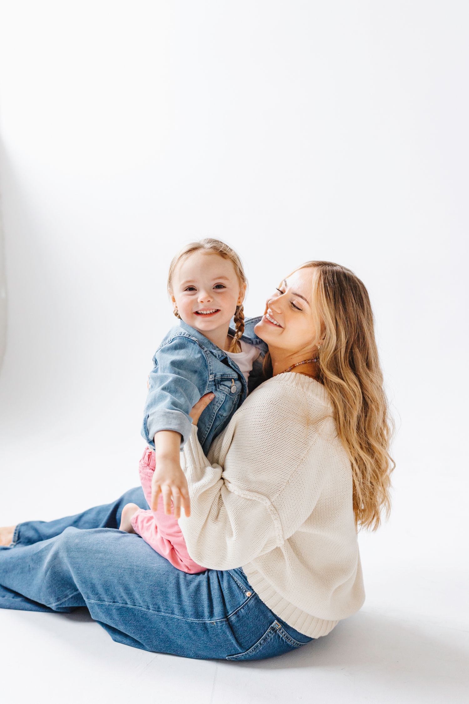 A tender moment of playful interaction between parent and child on a white background.