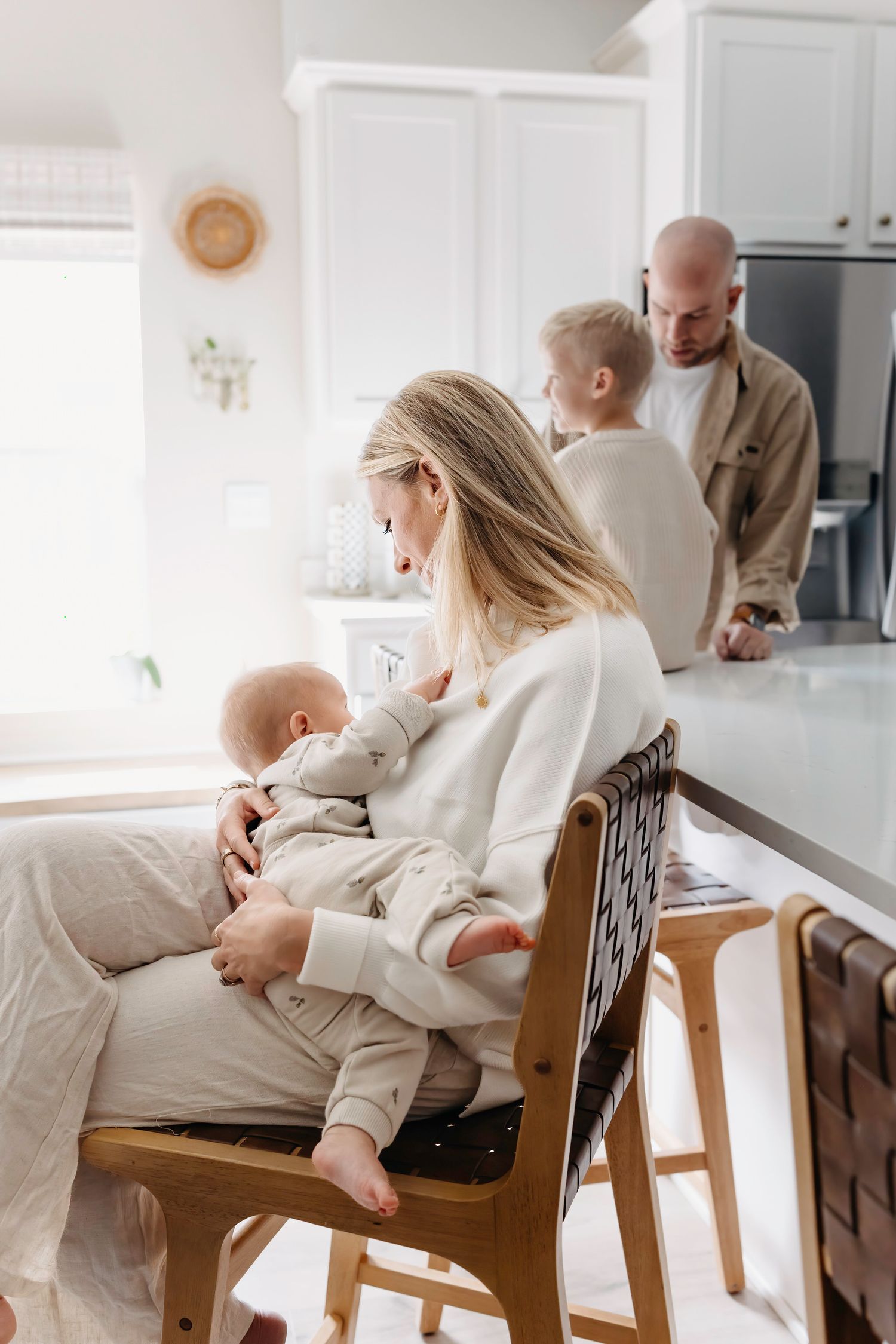 Family spending time together in bright modern kitchen with baby and toddler during morning routine.