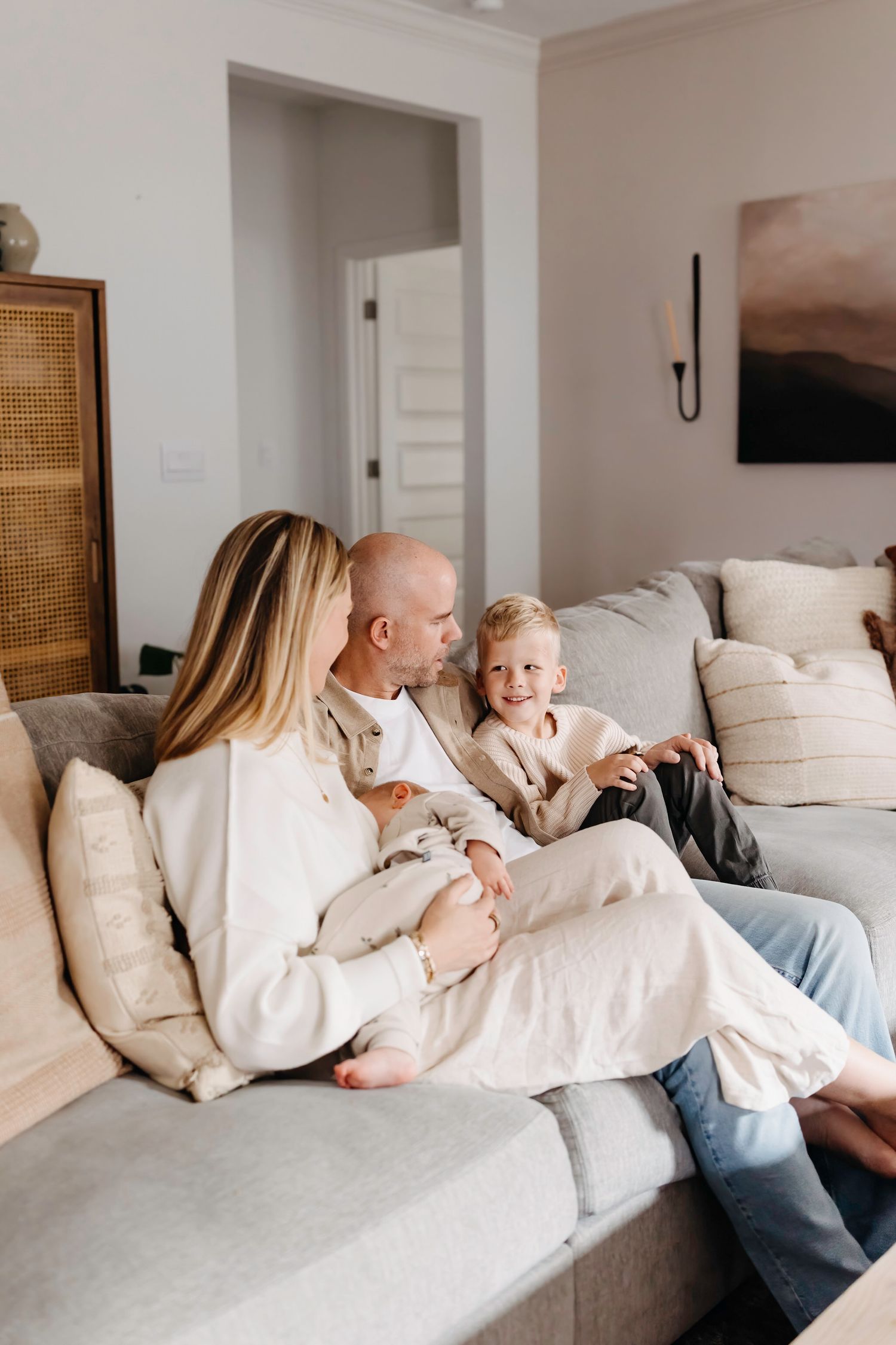 Family lounging together on a white sectional sofa in a bright, airy living room.