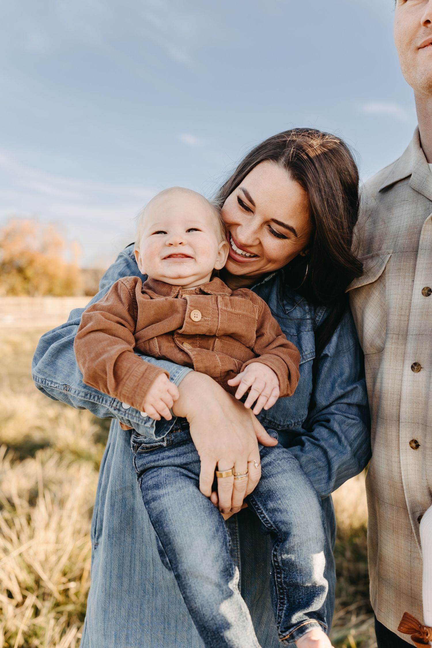 A family shares joyful moments together in casual attire against a natural outdoor backdrop during golden hour.