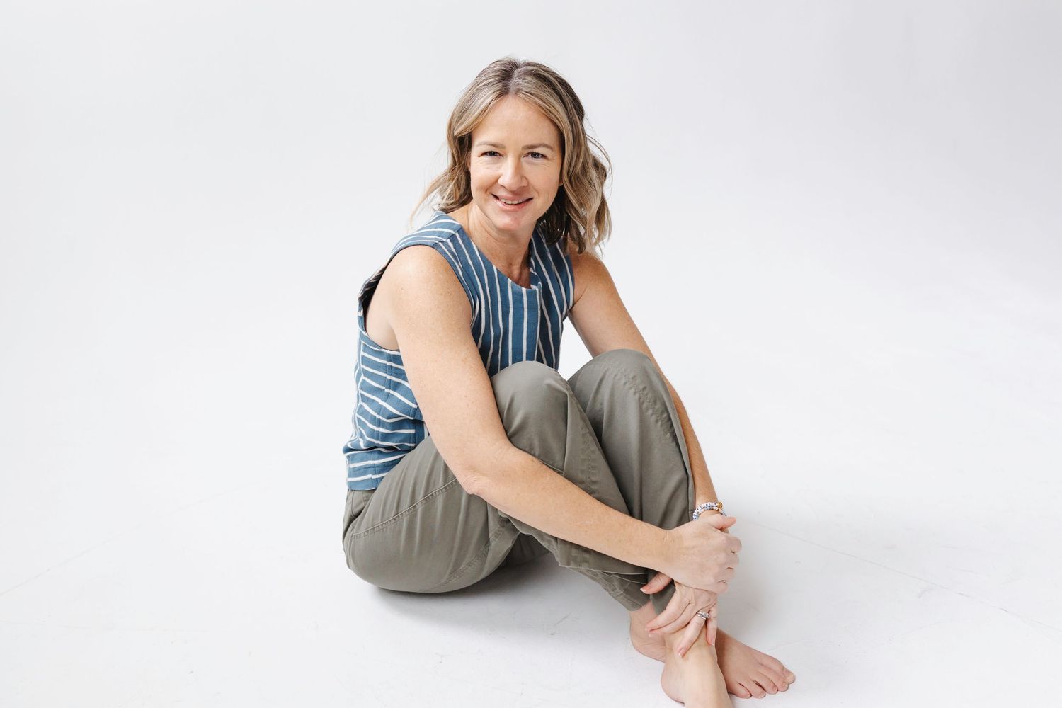 Person wearing blue and gray loungewear sits in relaxed poses against white backdrop.