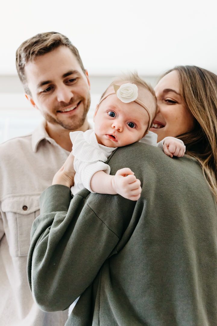 A loving family moment captured in a series of candid photos showing parents embracing their baby in warm neutral tones.