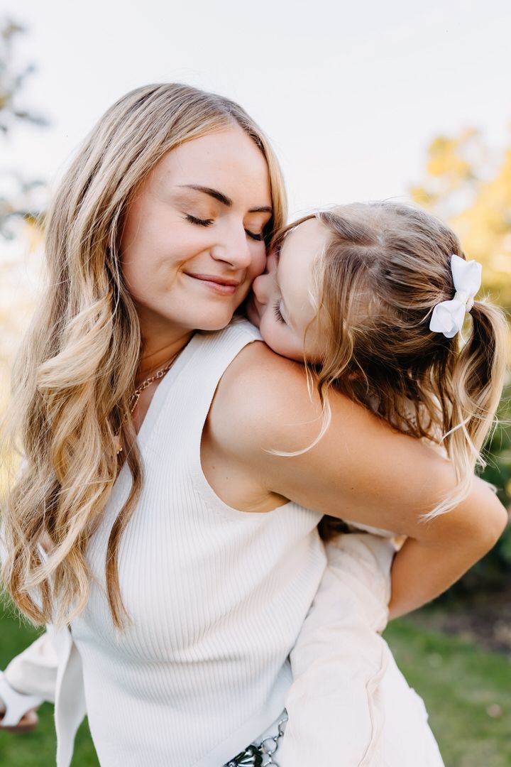 A mother and daughter share tender embraces and kisses in a series of candid outdoor portraits.