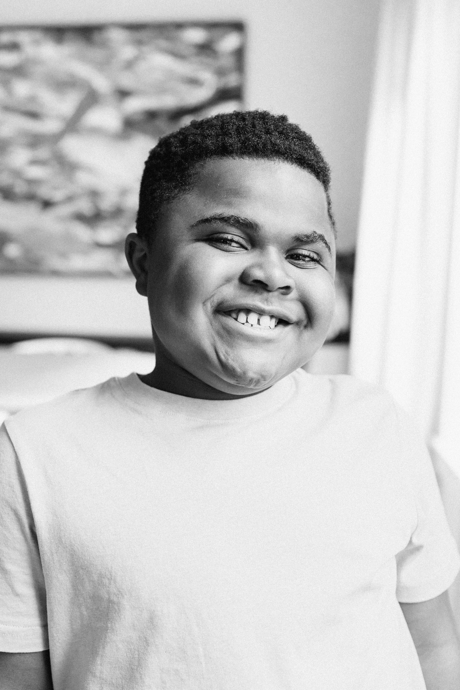 A series of black and white photos showing joyful expressions and bright smiles in a white shirt against a light background.