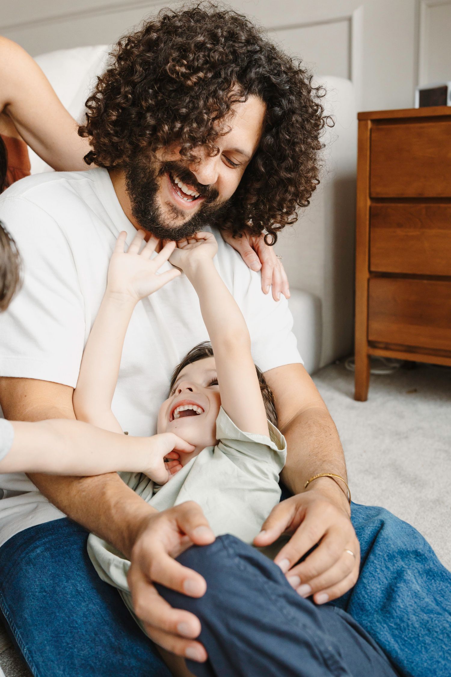 A playful moment on a carpet shows dad tickling young son.