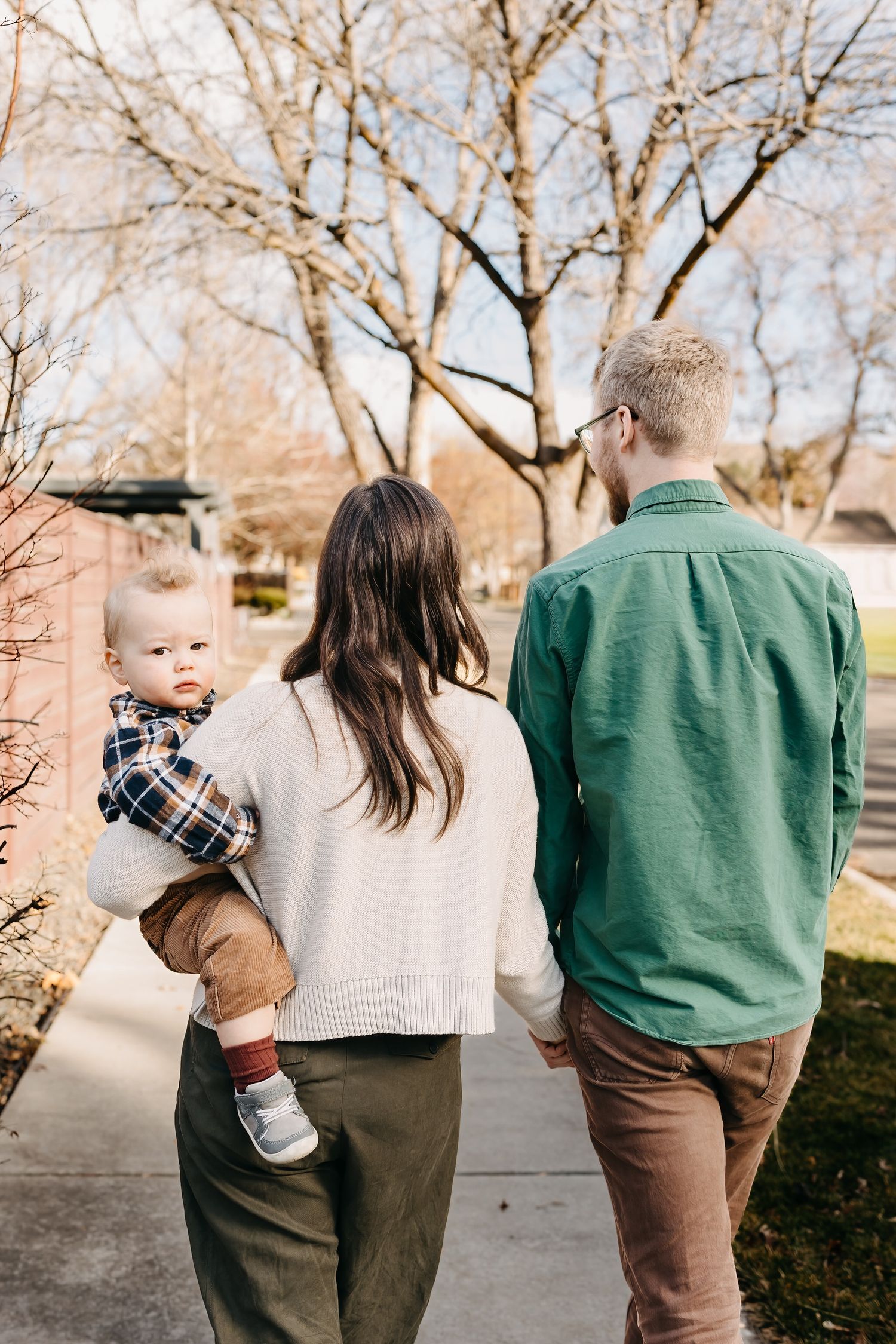 Family walking together in autumn garden wearing coordinated green and beige outfits in candid lifestyle photos.