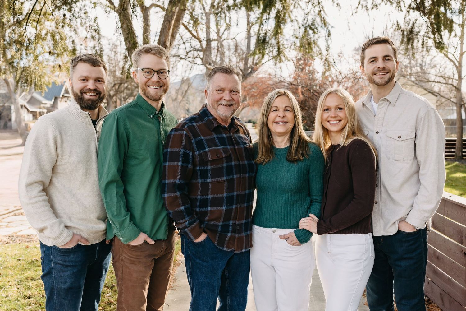 A group of people wearing coordinated blue, white and green outfits pose together outdoors for a family photo.