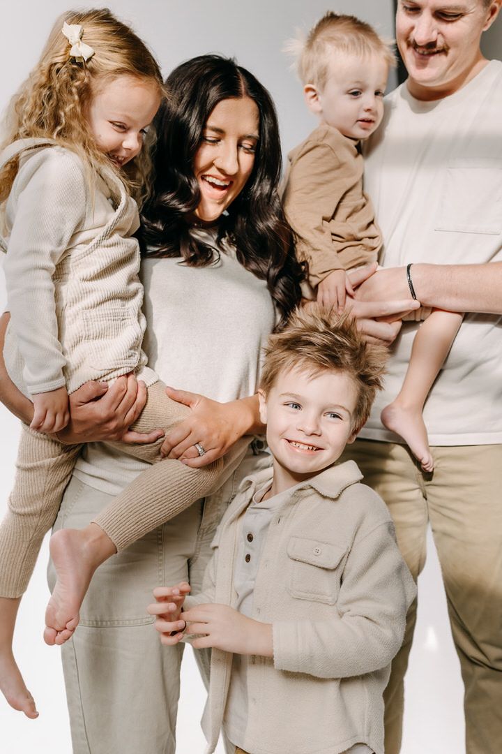 A series of candid family photos showing joyful moments in neutral beige and white outfits in a studio setting