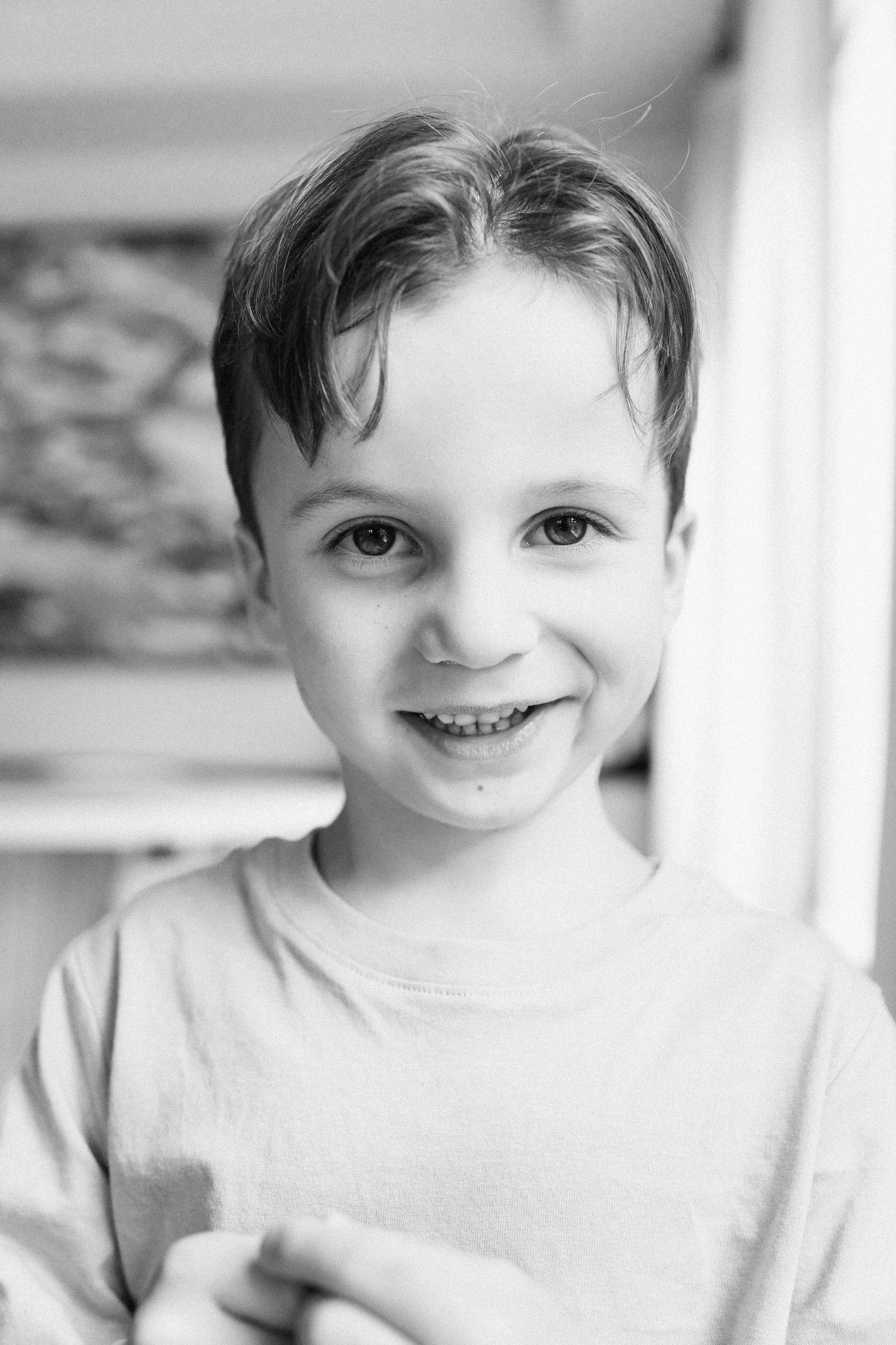 A series of four black and white close-up portraits showing joyful expressions and bright smiles.
