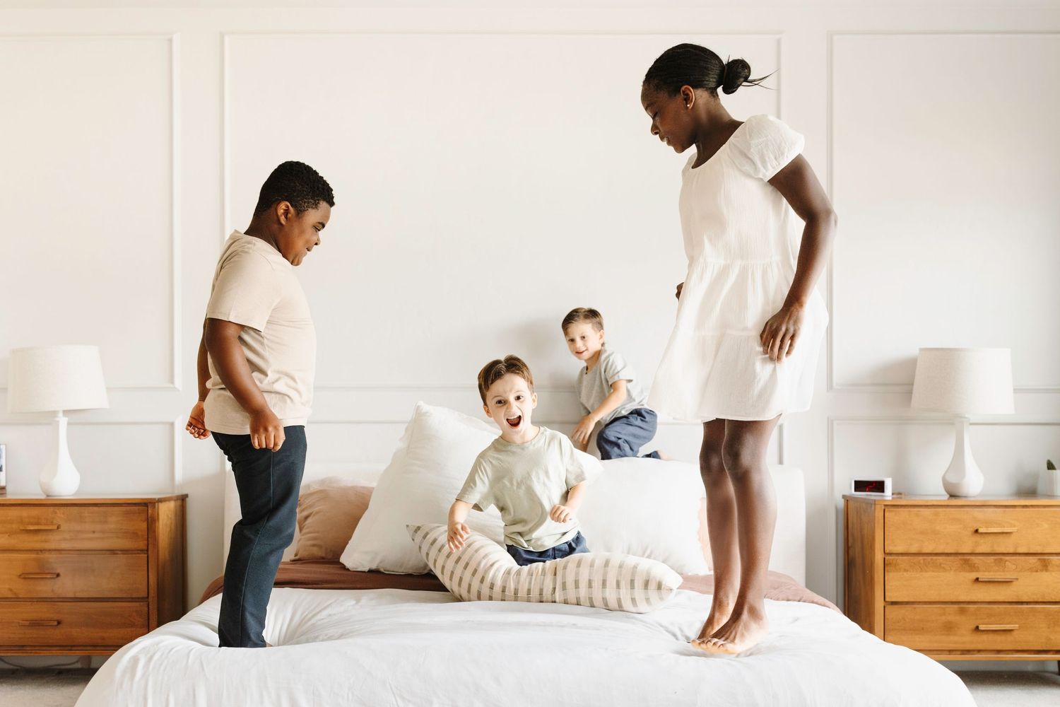 four siblings jump on mom and dads bed