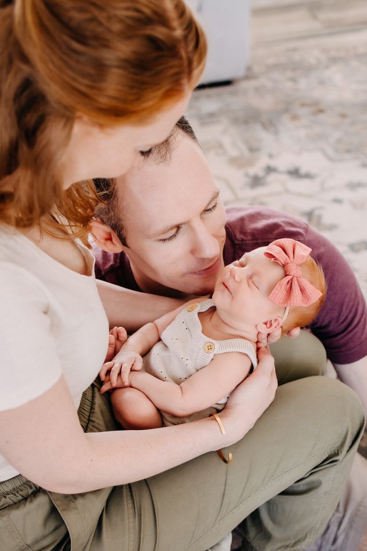 A tender moment between parent and baby is captured in a series of intimate photos on a light background.