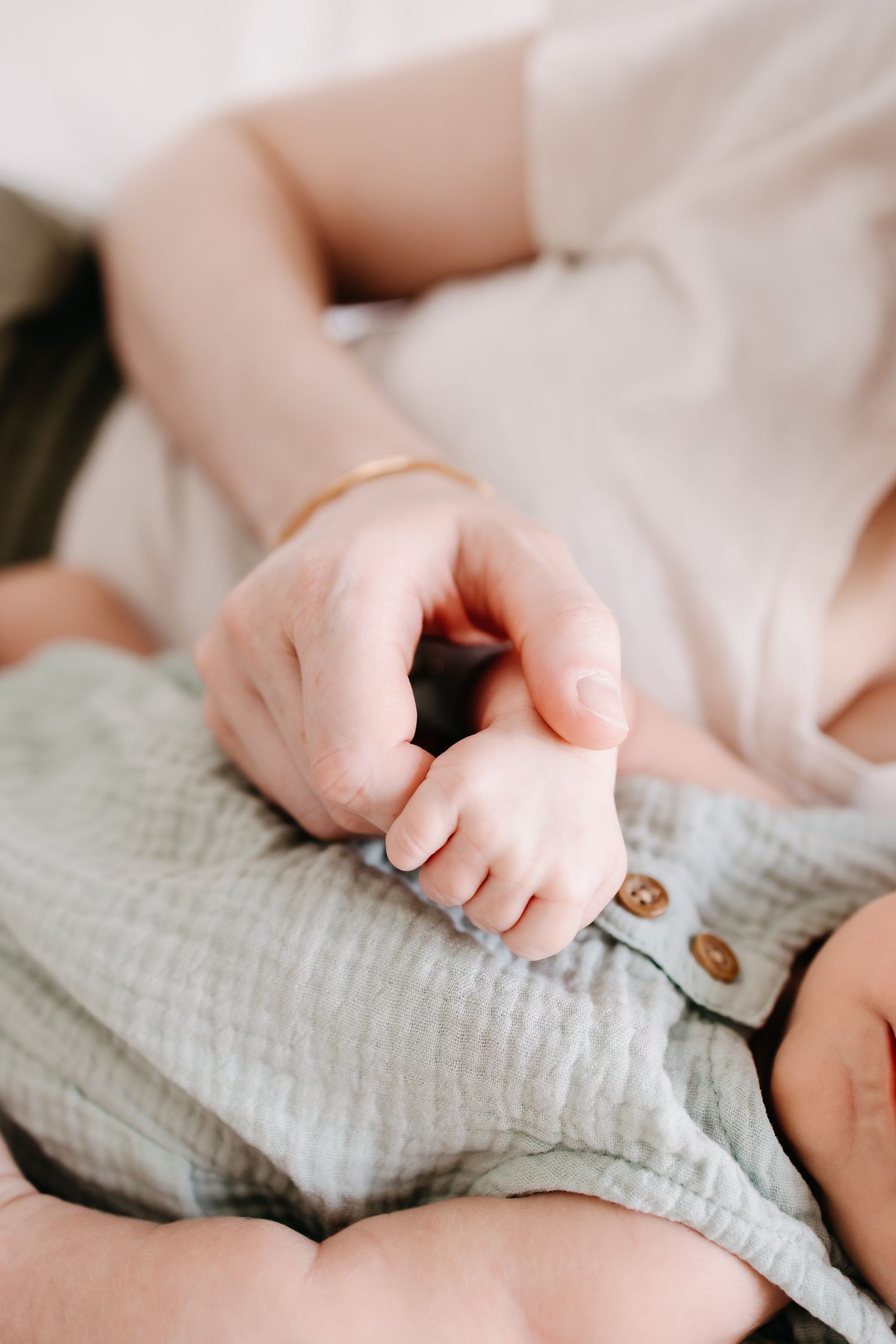 Close-up of tiny newborn baby fingers grasping soft gray fabric in a series of tender moments.