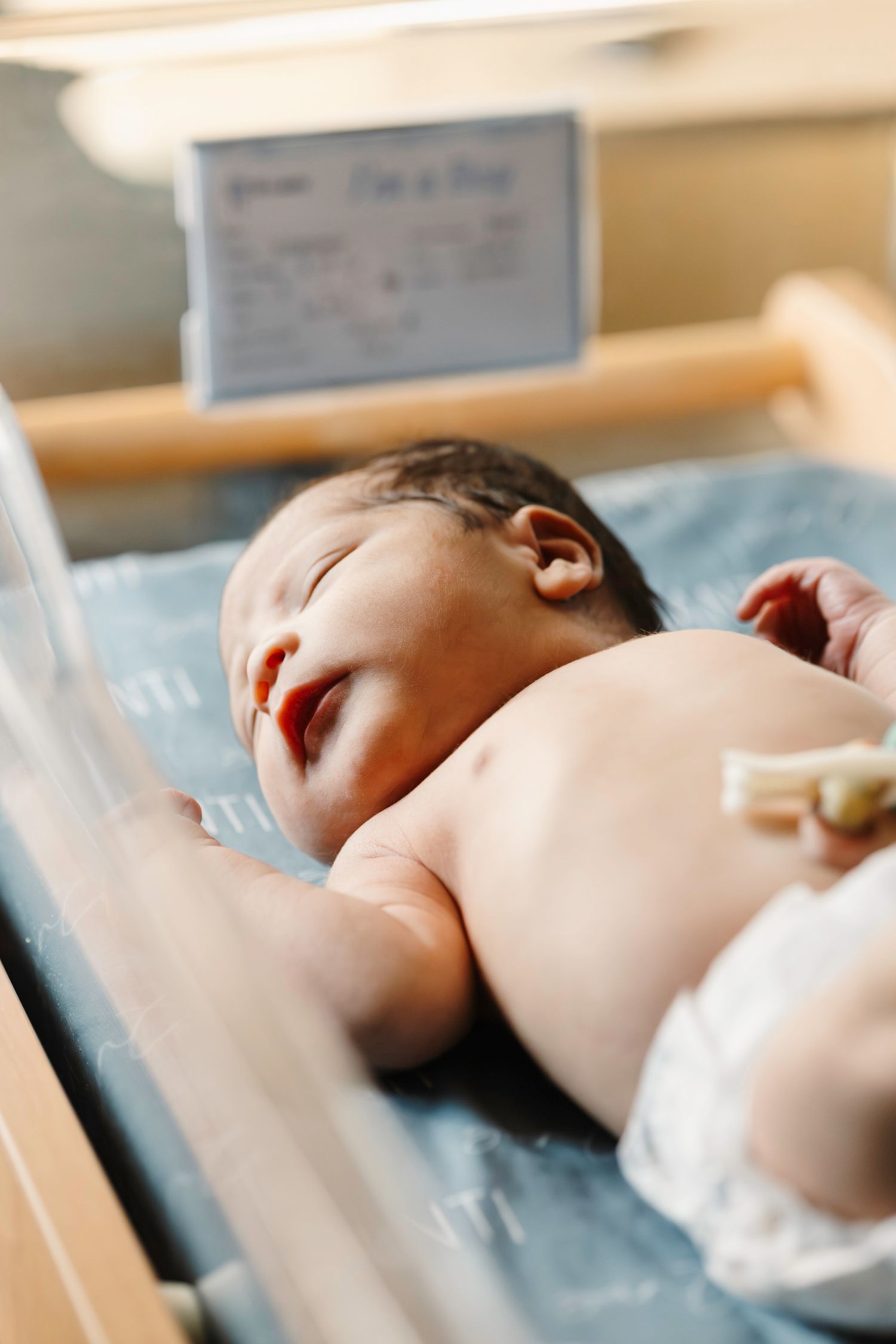 A newborn baby sleeps peacefully on a blue hospital blanket in a series of connected images.