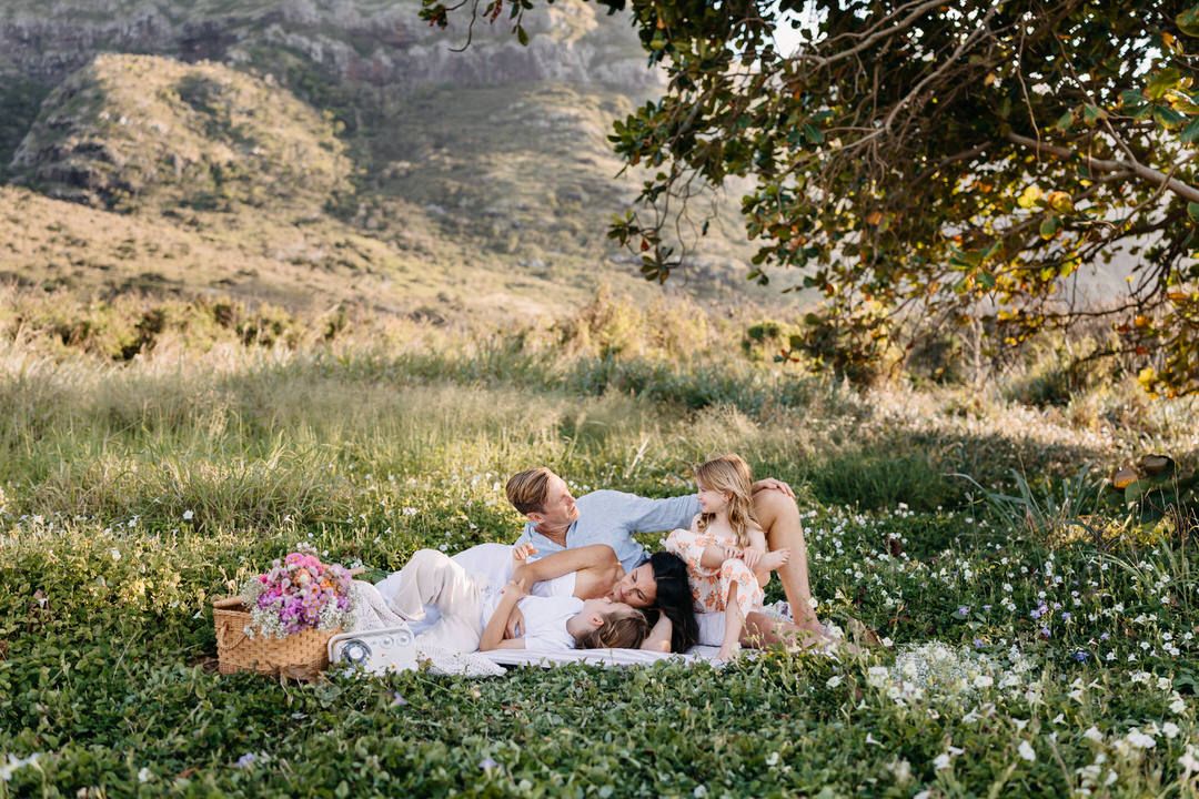 A family lying in a field of wildflowers during a sunset photoshoot.