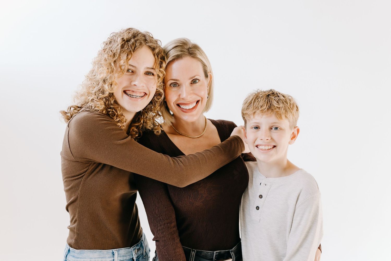 A family wearing black and white outfits embraces and laughs together against a light background.
