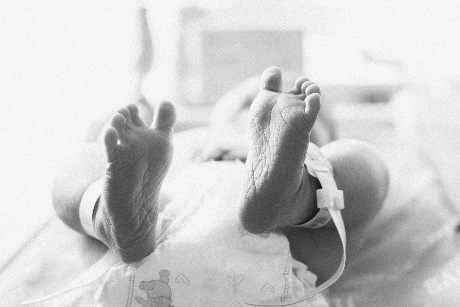 A collection of black and white photographs showing newborn baby feet in soft focus.