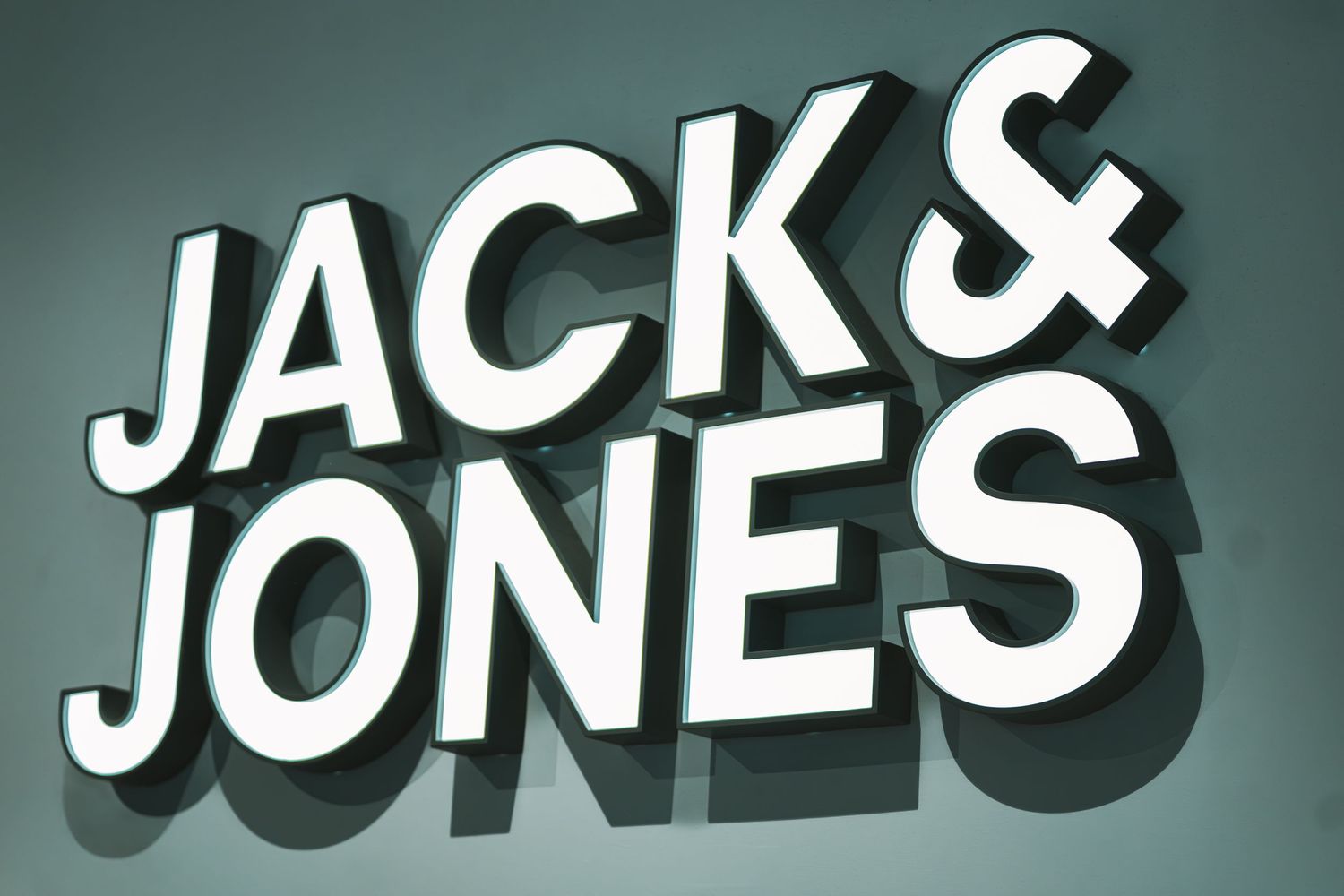 White illuminated text signage against a teal background.