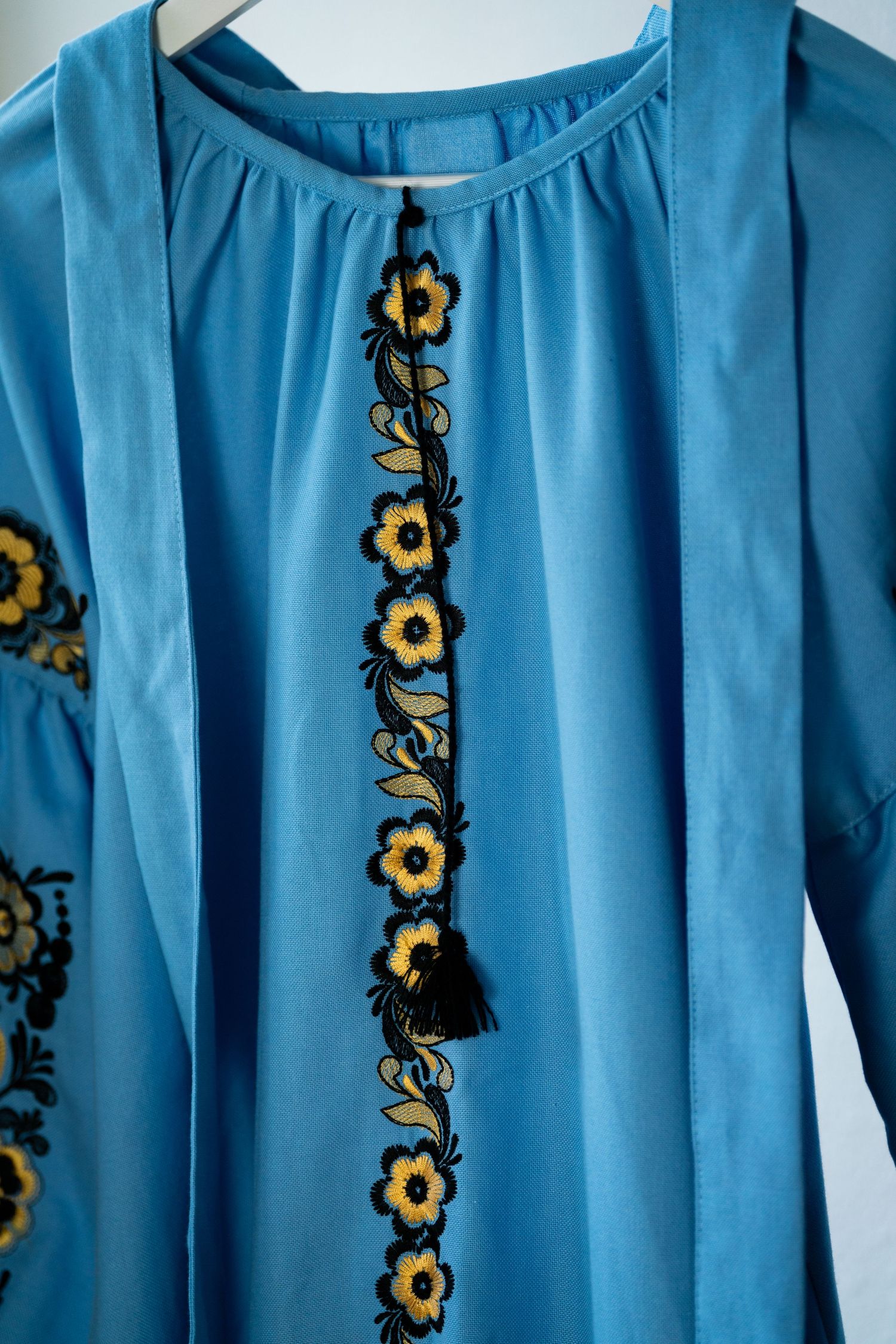Light blue dress with yellow floral embroidery pattern along the sleeves.