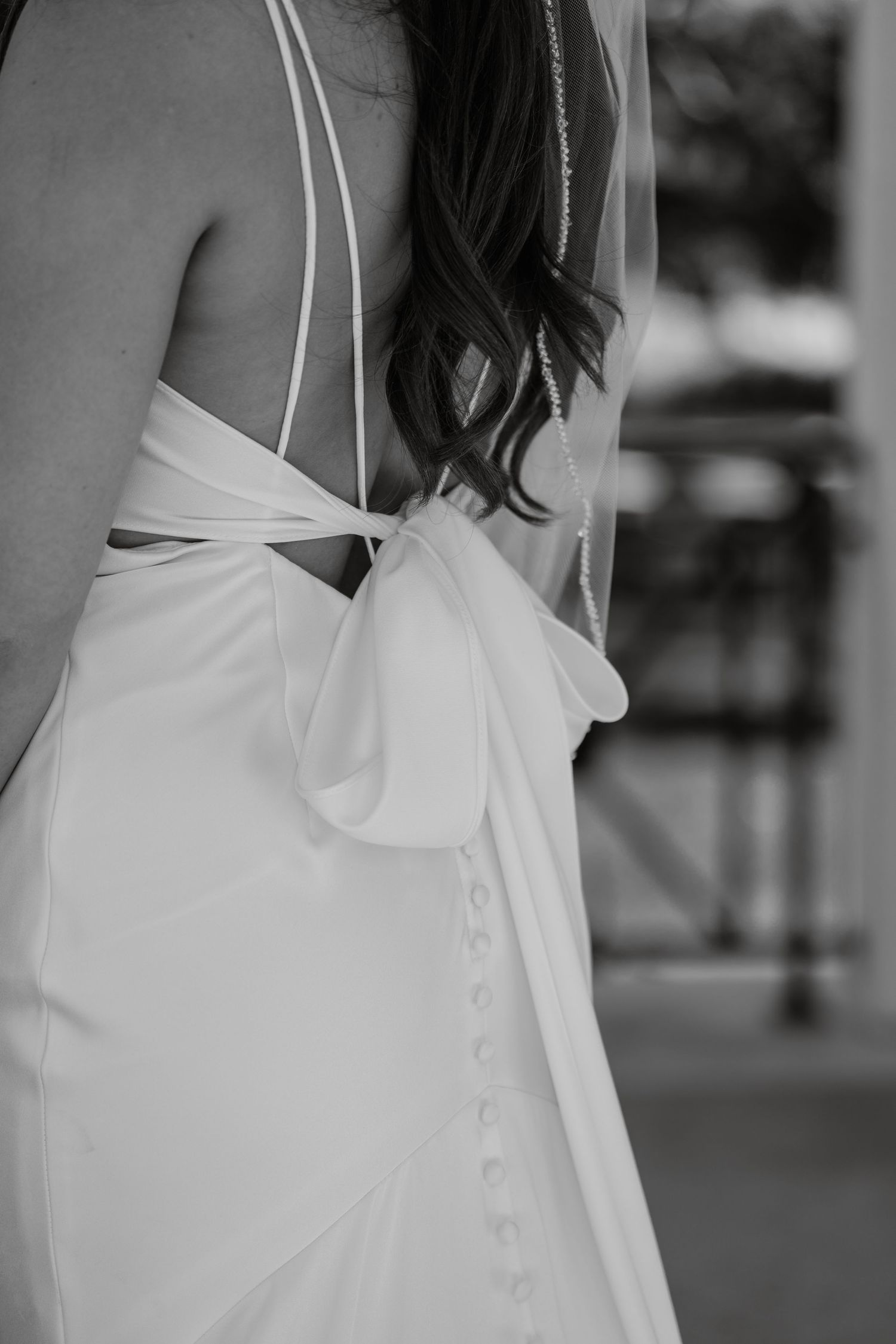 Back detail of white wedding dress showing delicate buttons and ruffles in black and white.