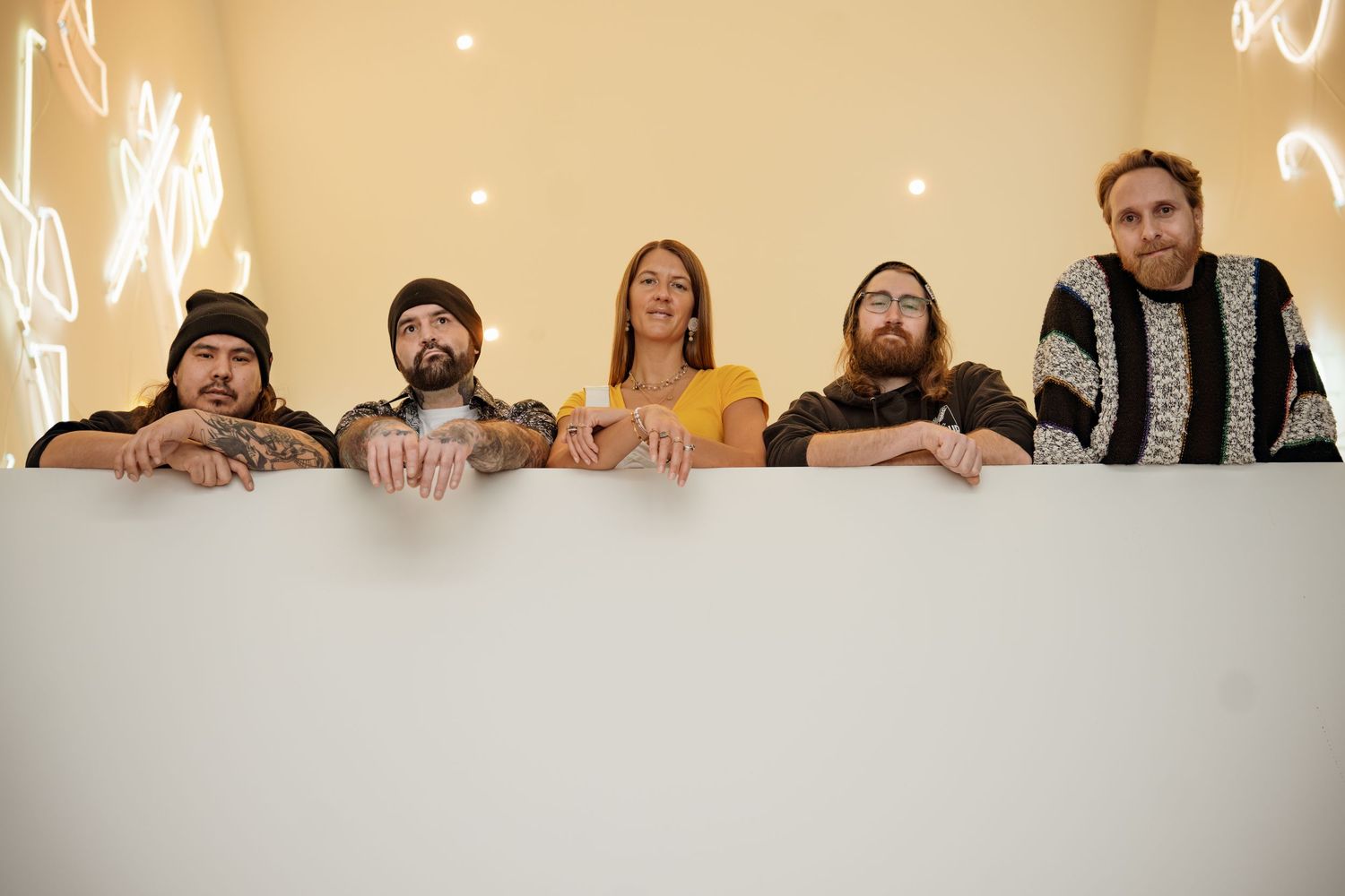 Band members posing together on white steps with warm lighting above.
