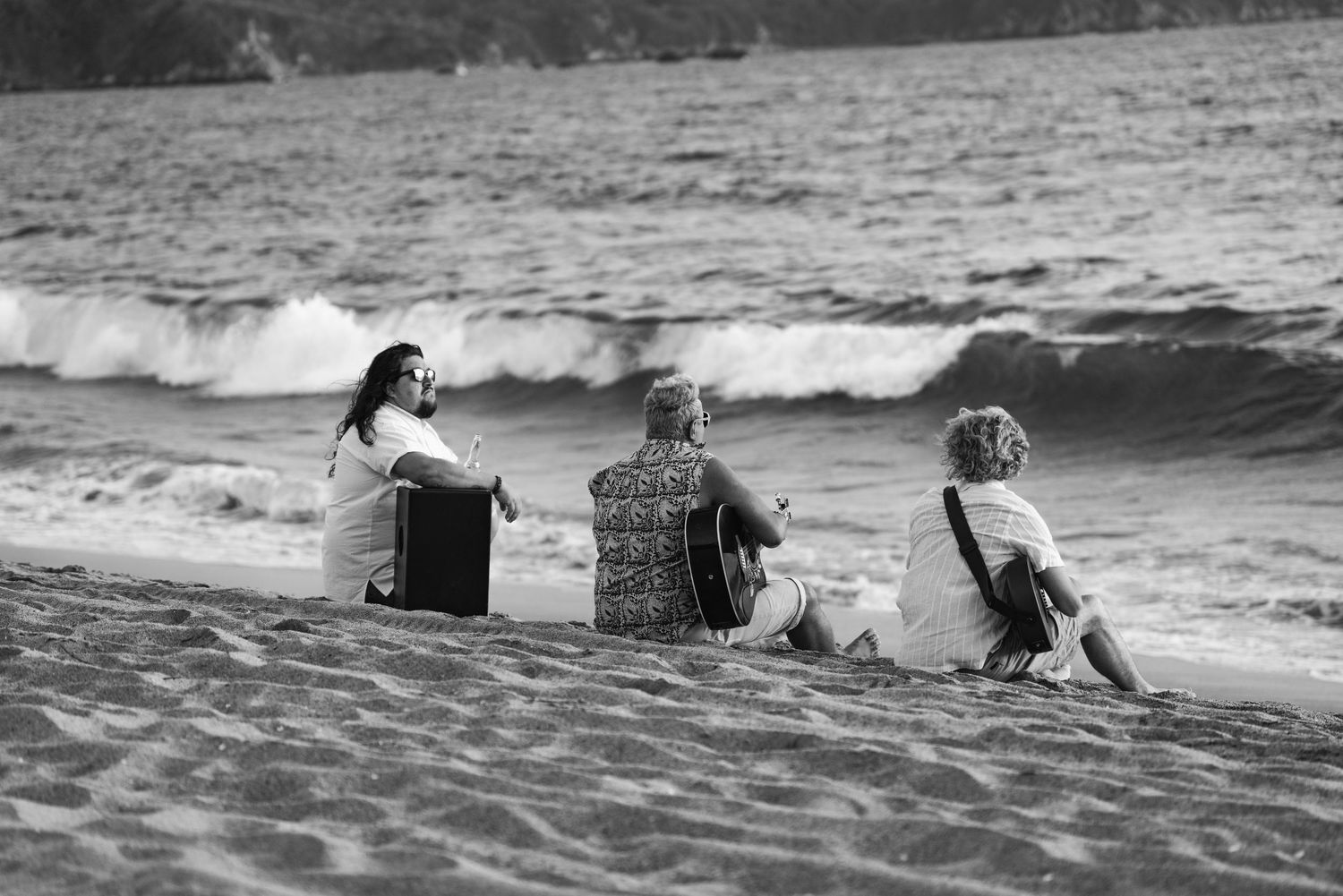 People swimming and playing in ocean waves at the beach in black and white.