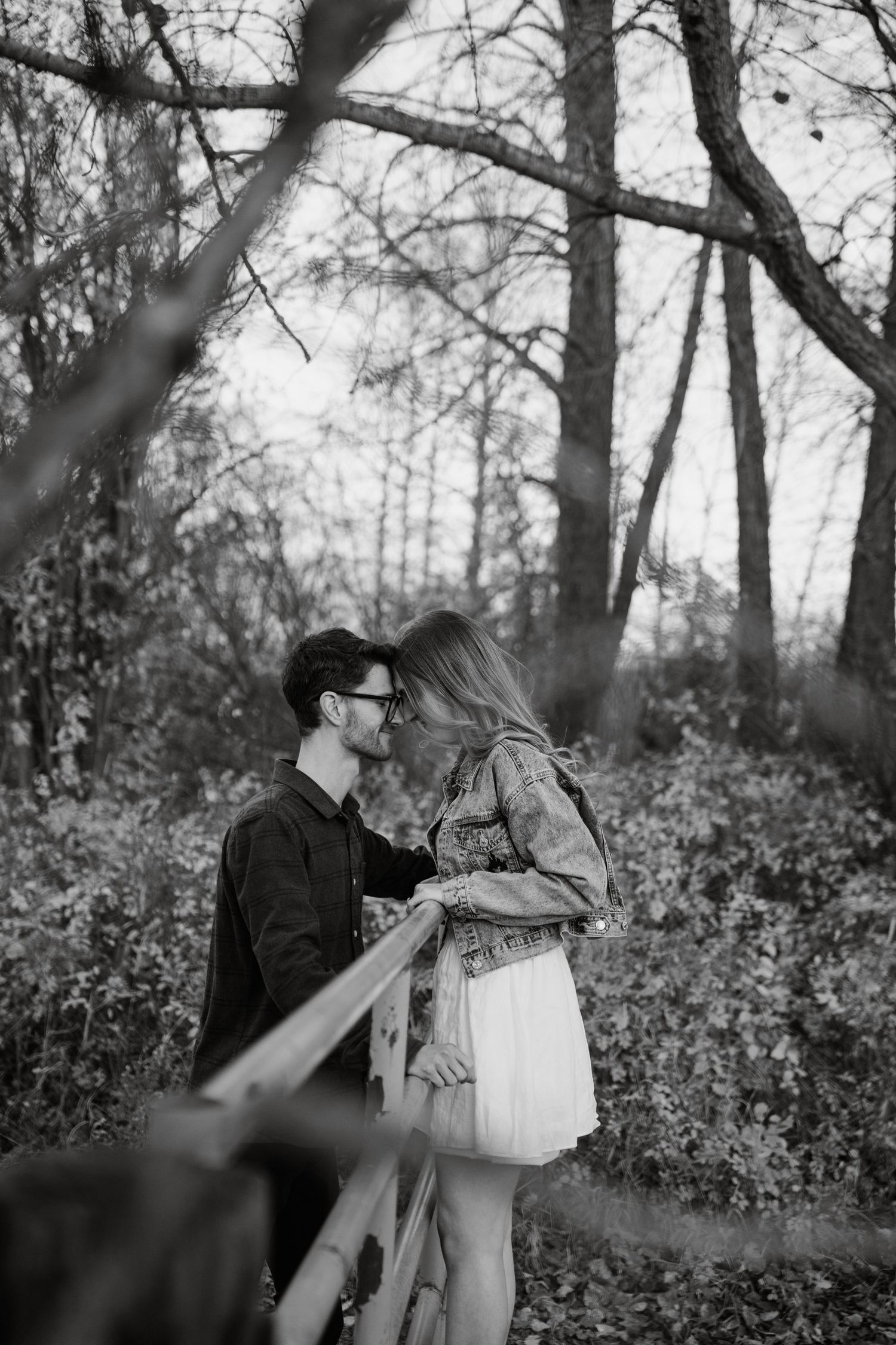 Couple walking through wooded area in black and white photography.