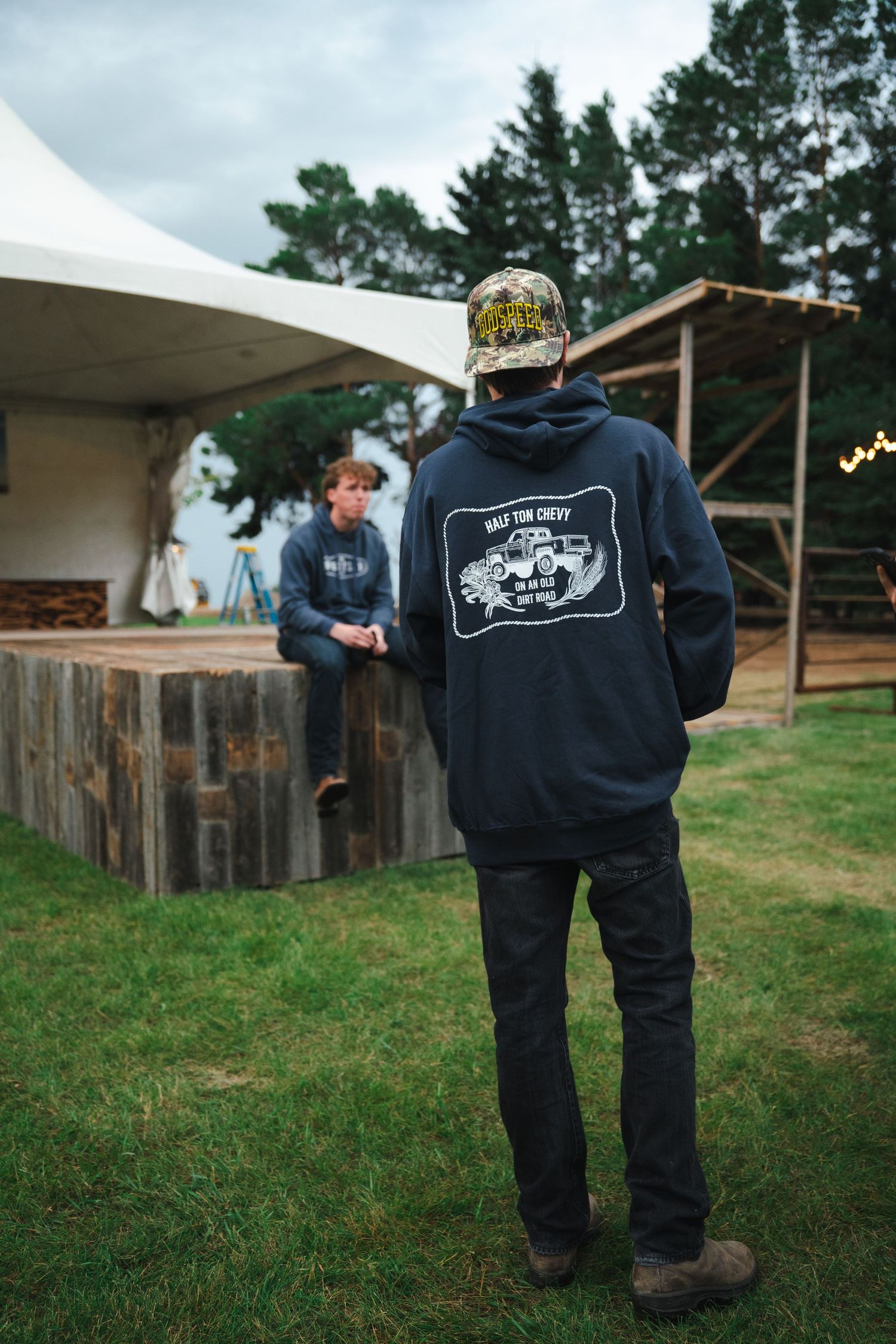 People in dark hoodies with guitar designs standing in an outdoor venue.