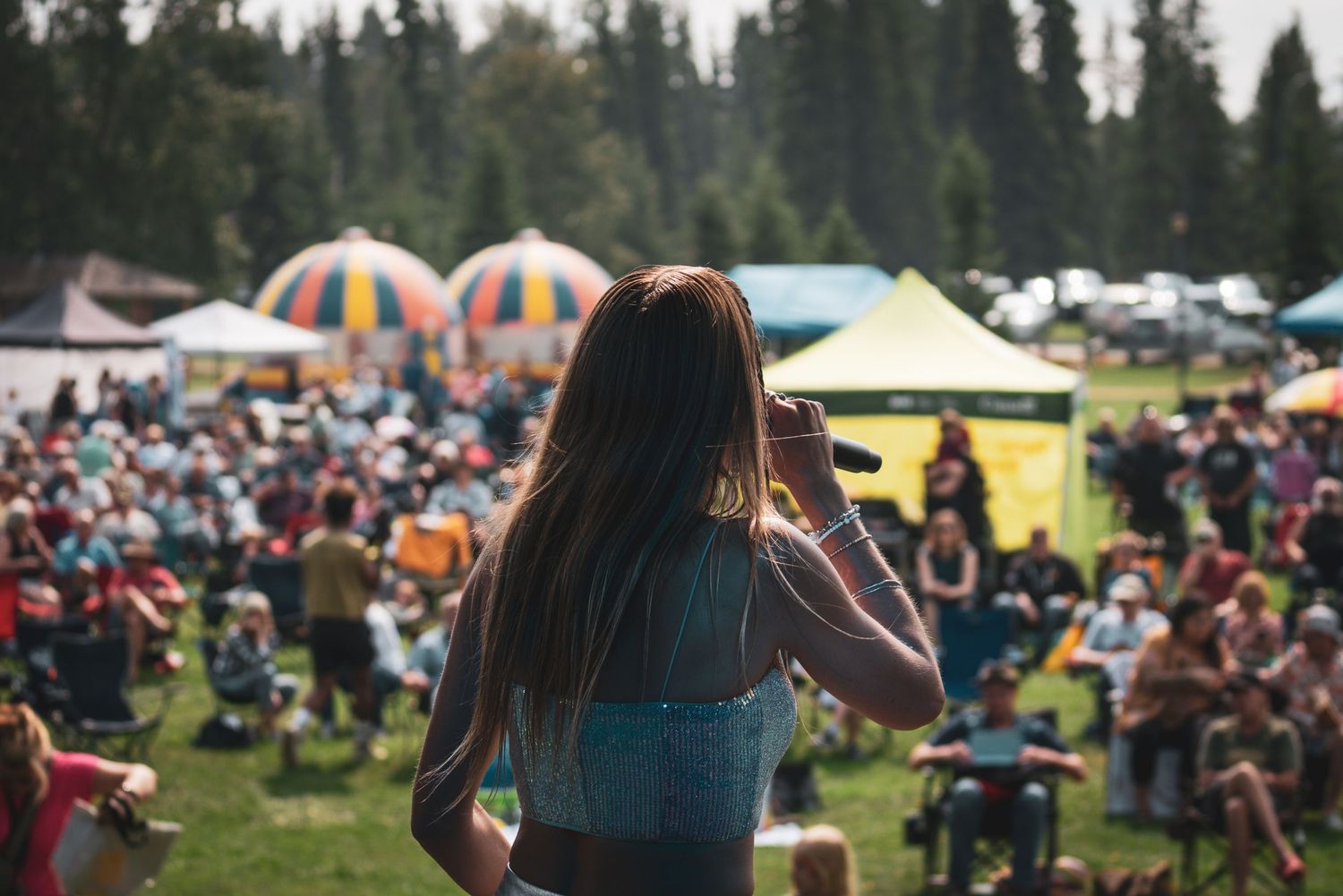 Festival crowd enjoys outdoor concert with mountain scenery and colorful decorations.