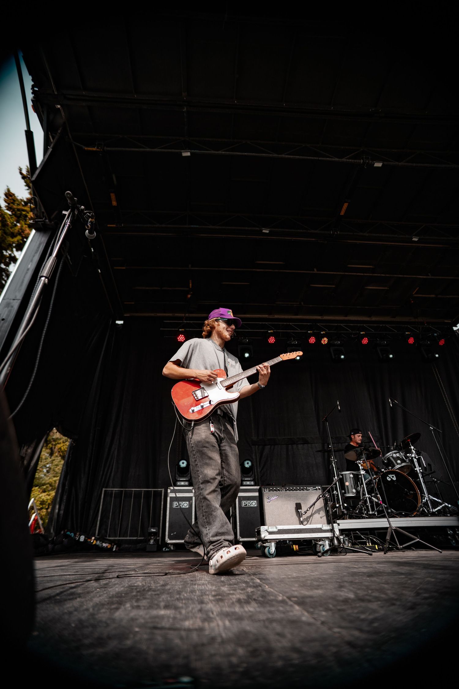 Guitarist performs on dark stage with dramatic lighting during live concert performance.