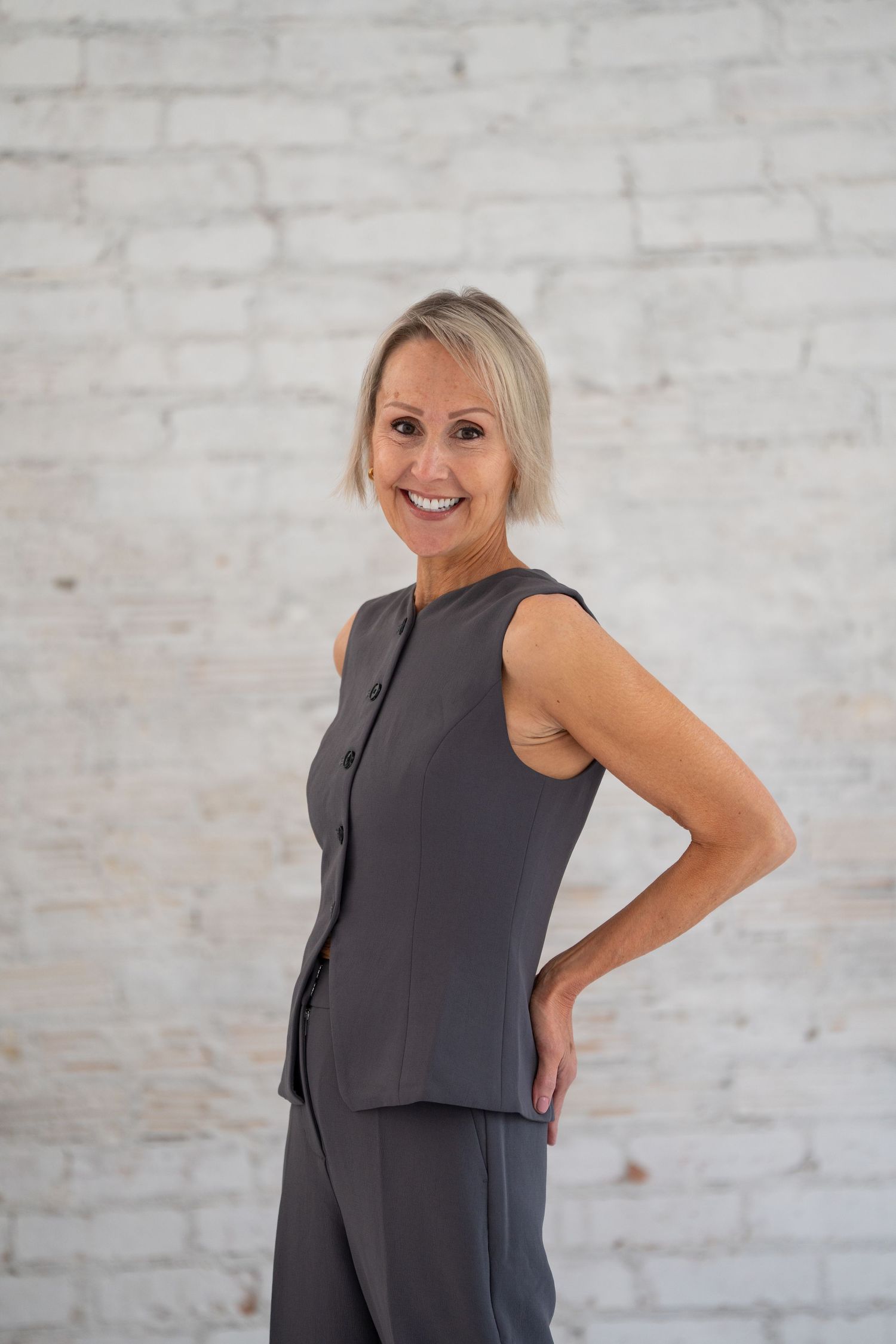 Studio fashion portrait against white brick wall background.