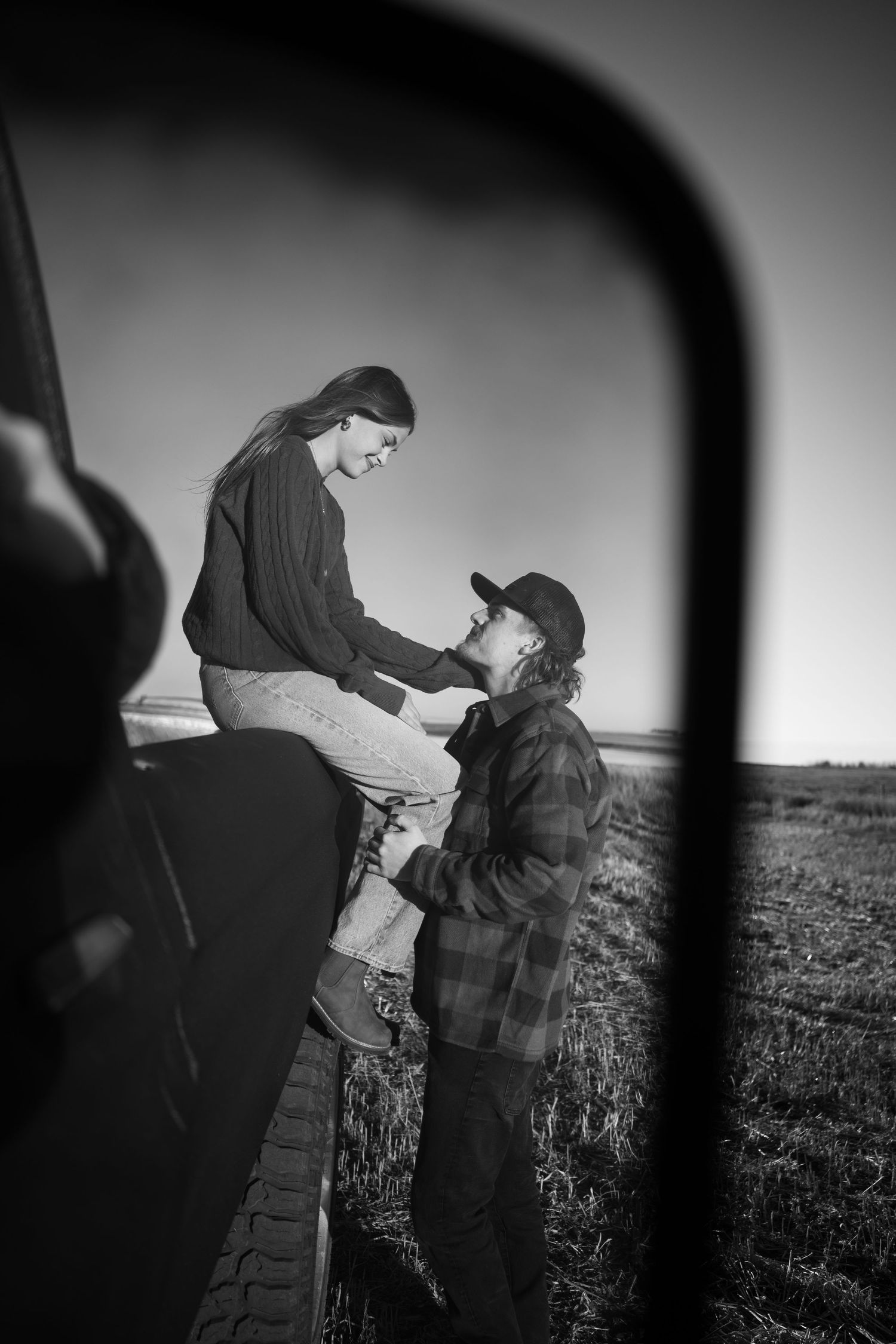 Silhouettes of two people embracing in a field during sunset.