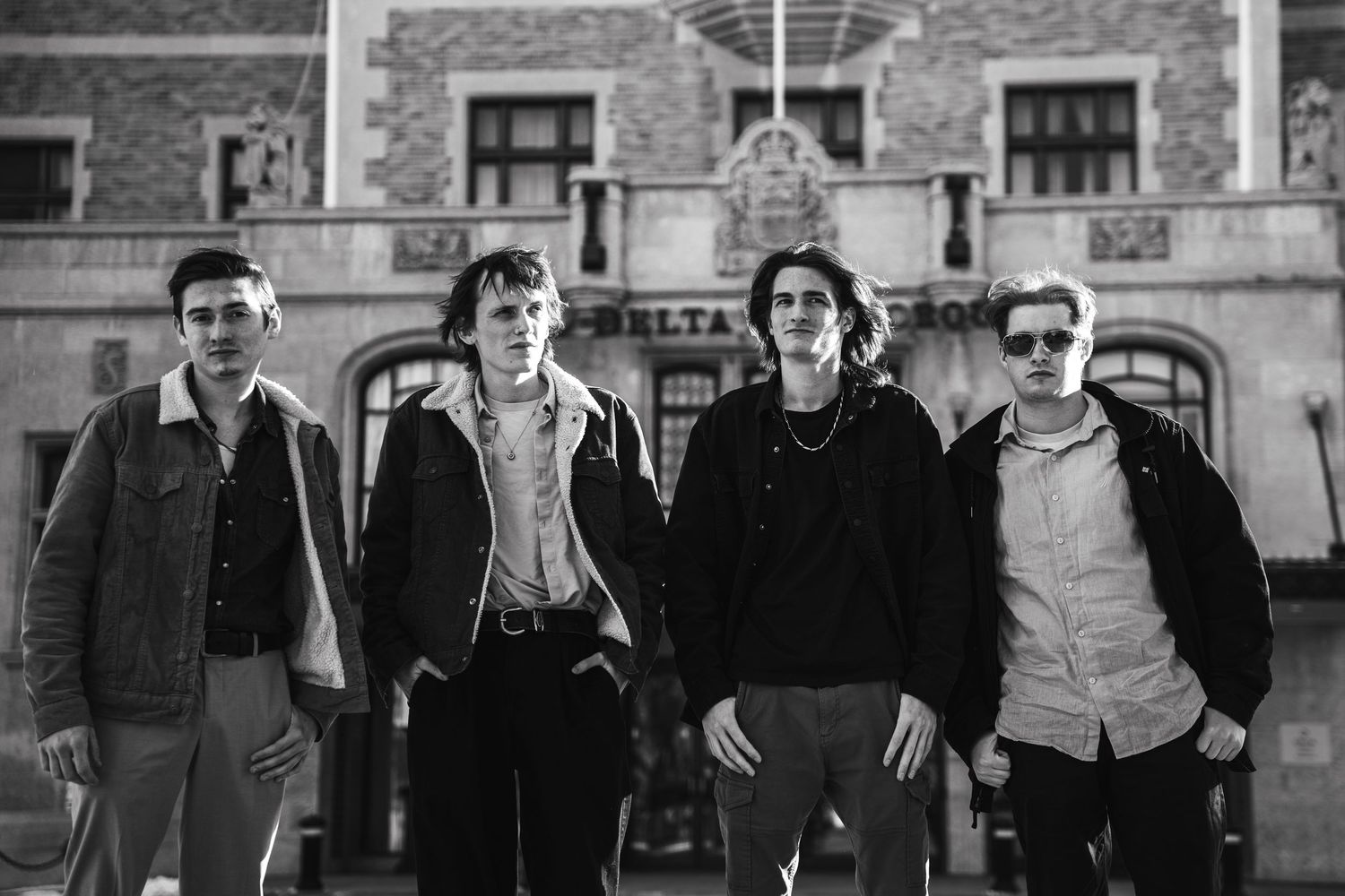 Group posed against brick wall in vintage black and white style.