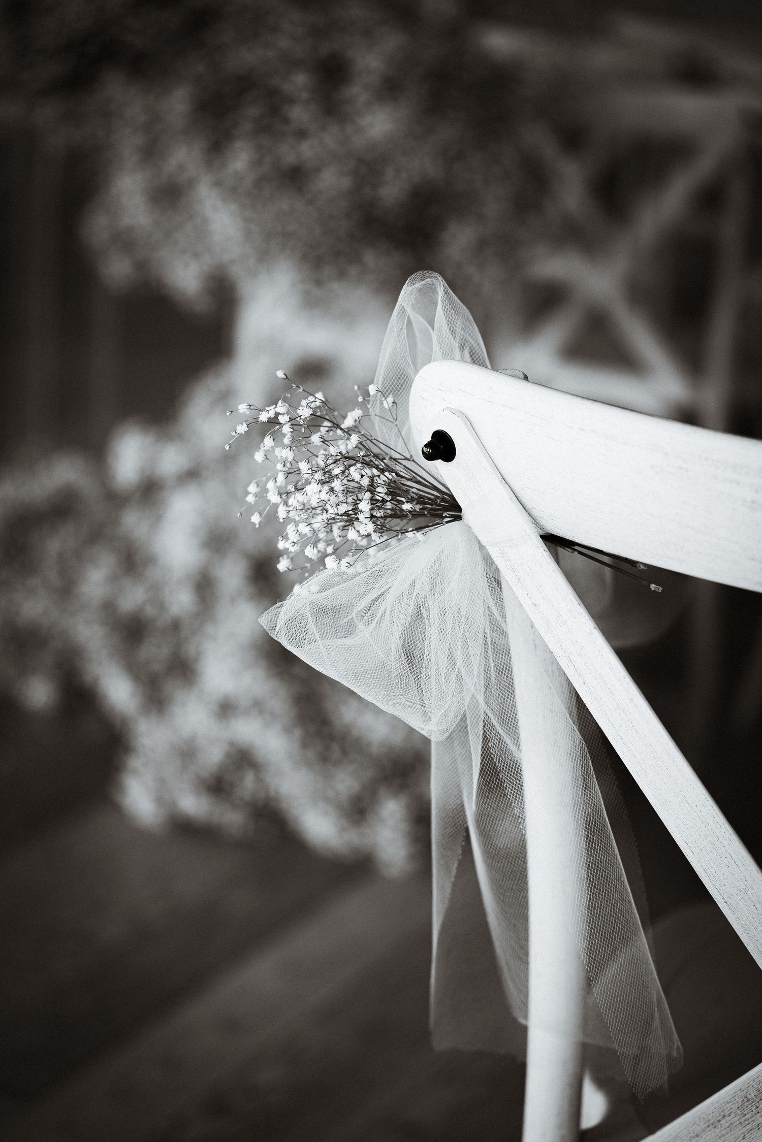 White wedding ceremony chairs decorated with delicate tulle and baby's breath flowers.
