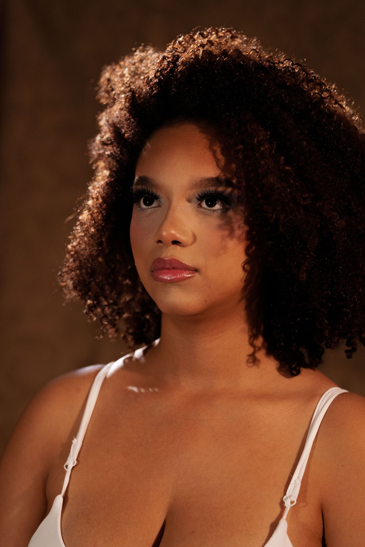 Warm-toned studio portraits featuring natural curly hair and white tank top.
