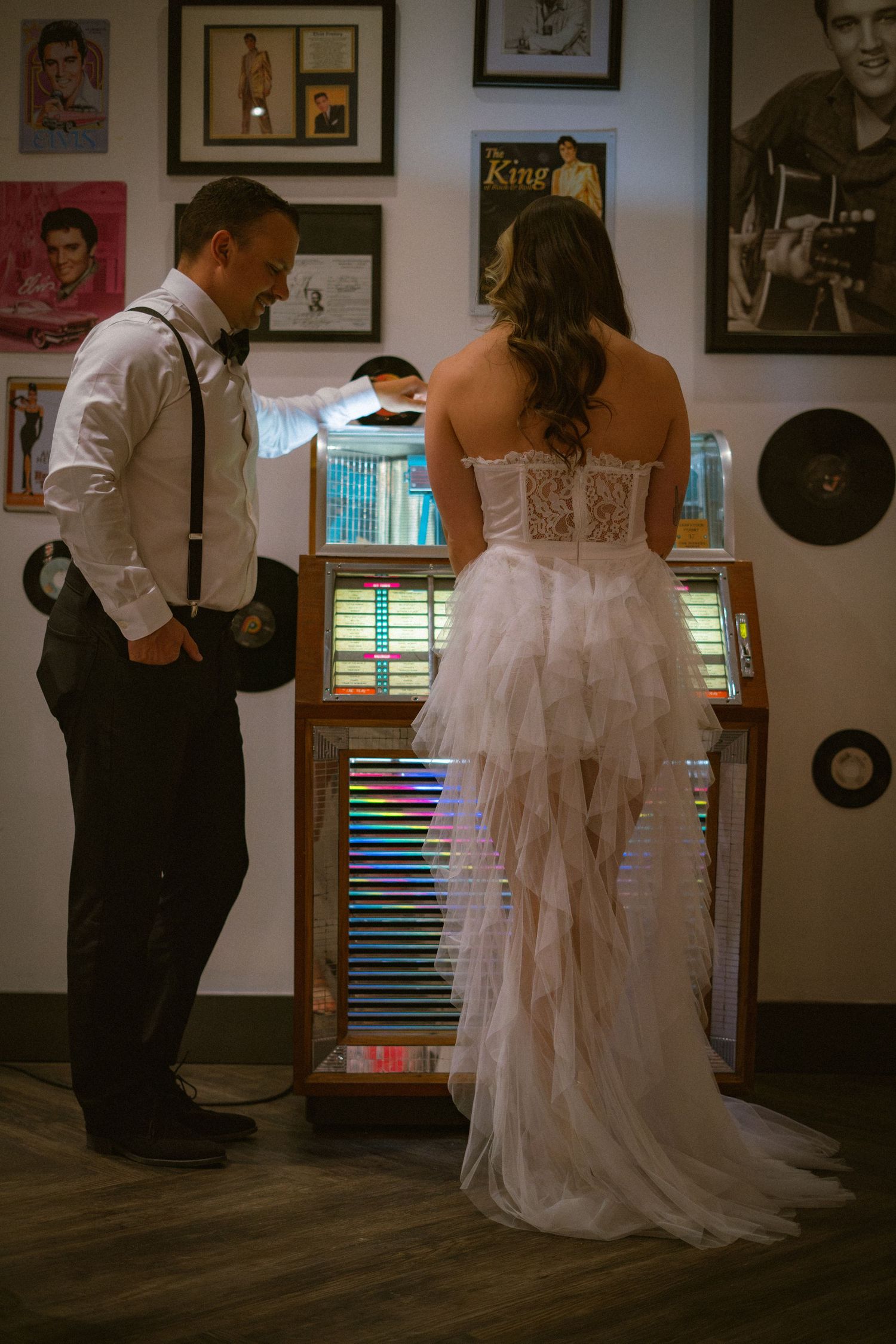 Wedding couple in formal attire dancing in room decorated with vintage music posters.