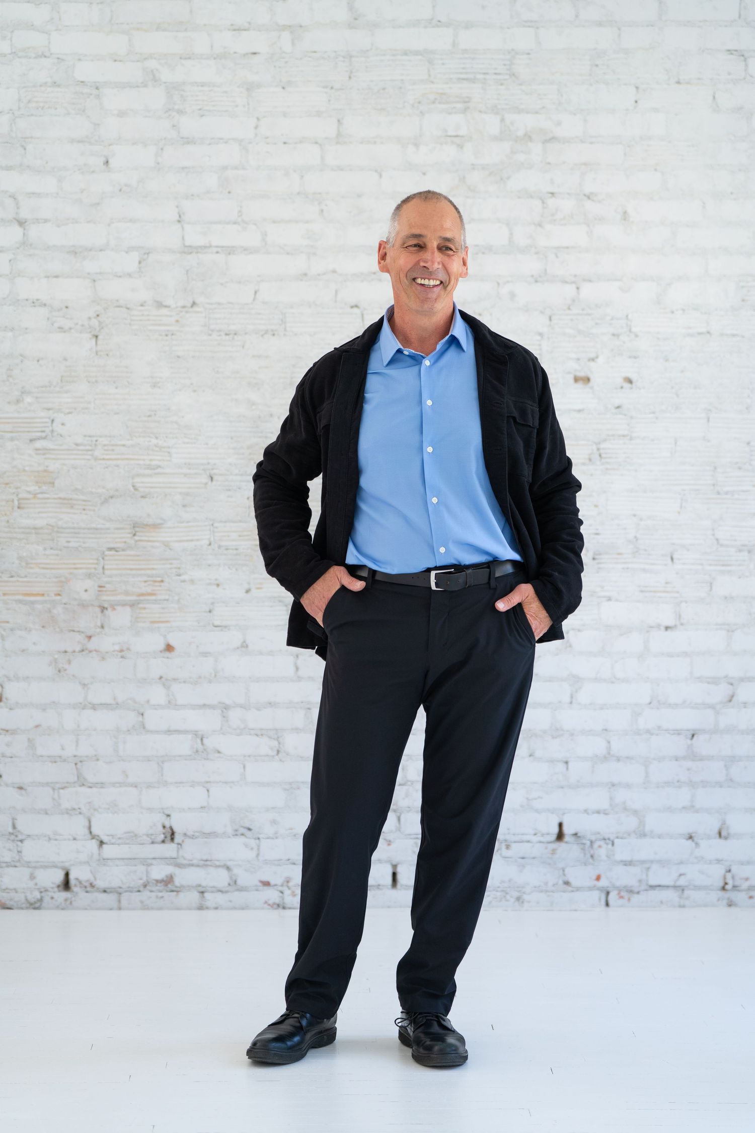 Professional studio portrait against white brick wall background.