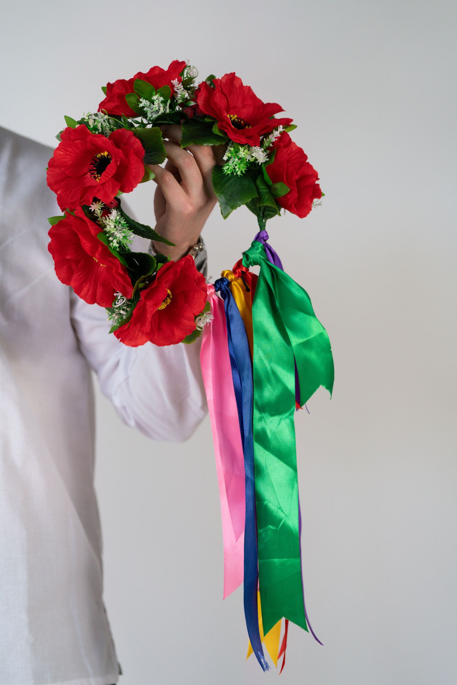 Red flower crown with colorful ribbons displayed from multiple angles.