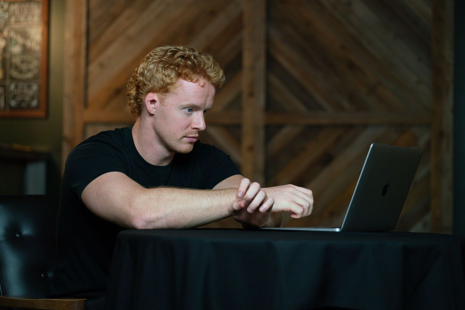 Person working on laptop in dark rustic wooden interior setting.