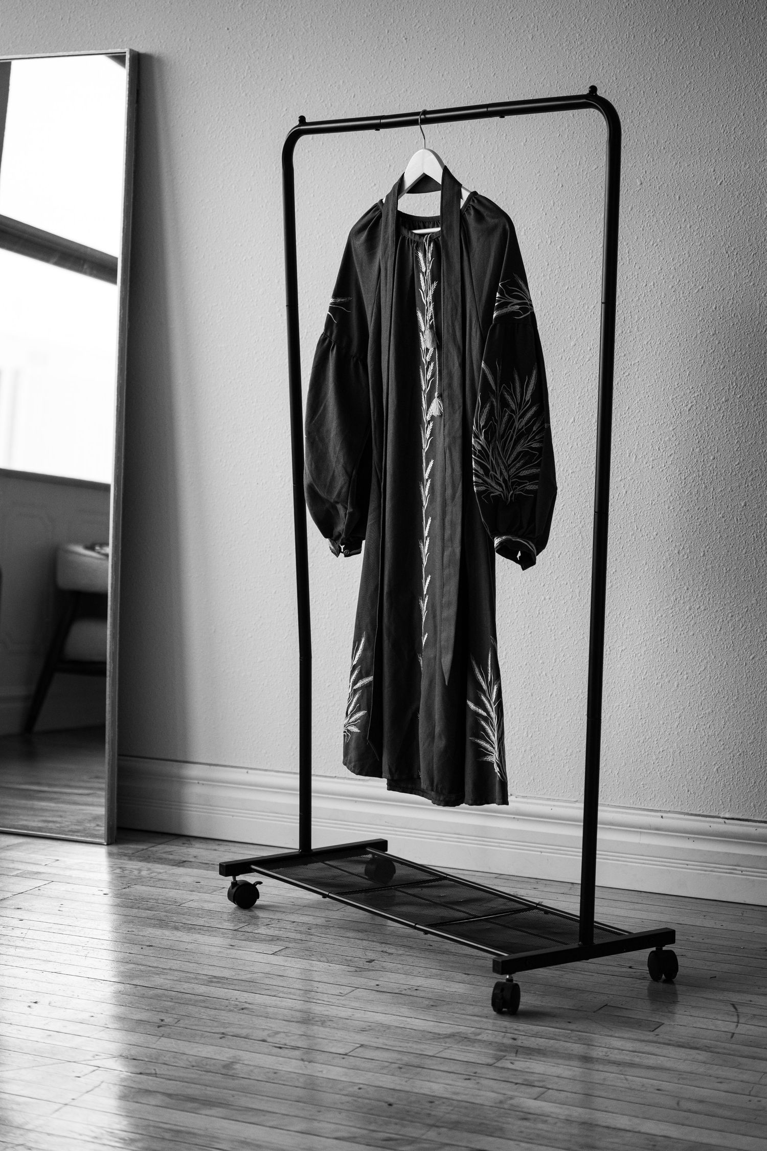 Black clothing rack with dark garment displayed in minimalist setting.