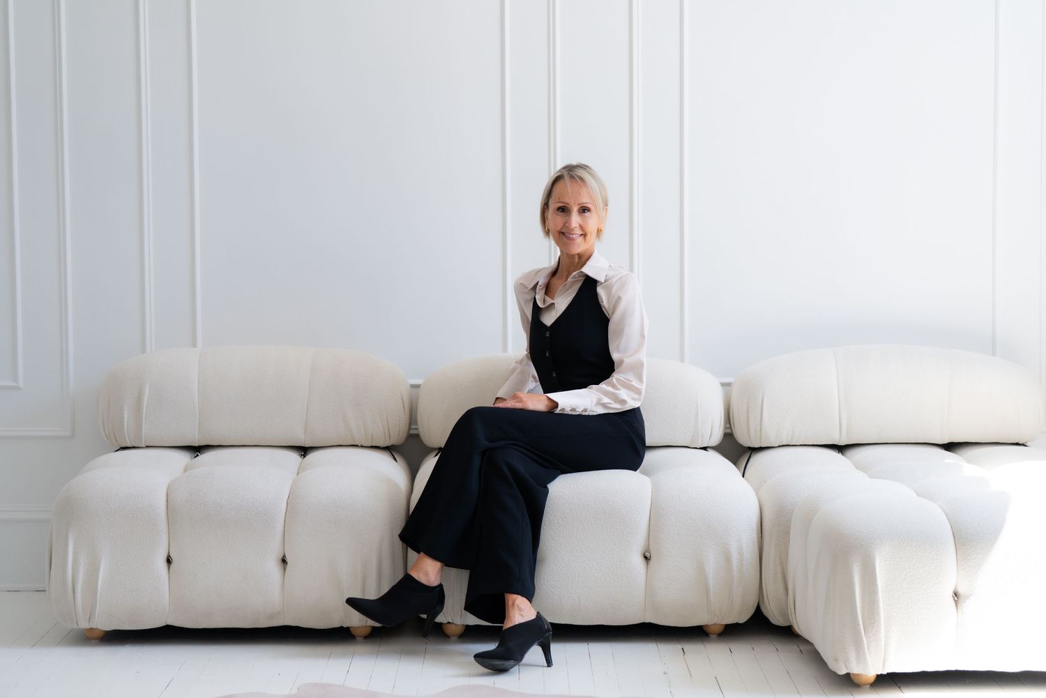 Artistic portrait series of someone sitting on a minimalist white sofa against a white wall.