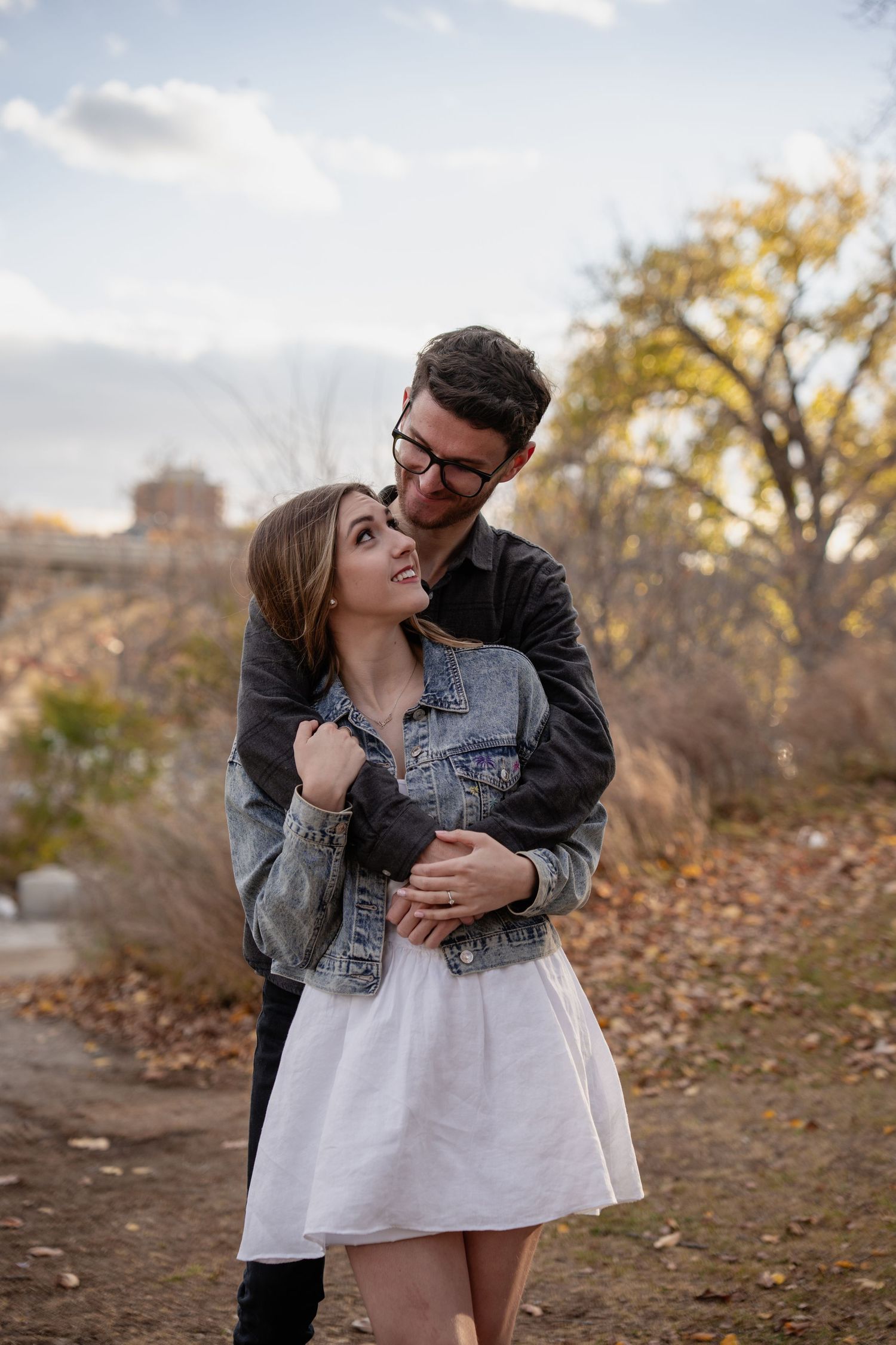 Couple in casual denim and white sharing tender moments in an autumn setting.