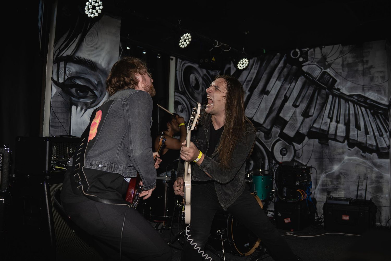 Concert venue with graffiti walls and performers on stage in black and white.