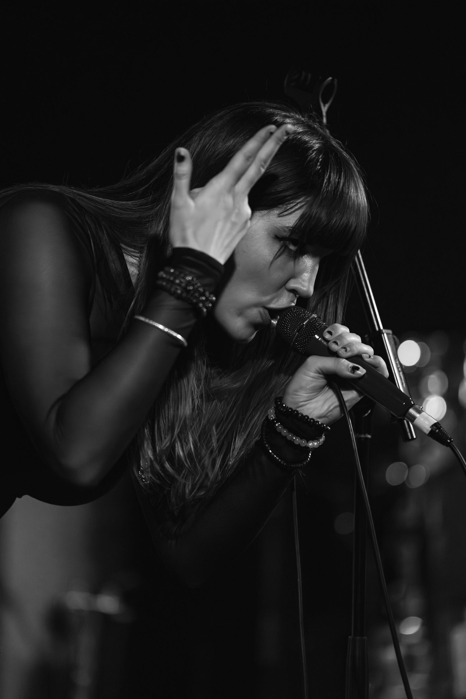 Dramatic black and white shot of performer singing into microphone during concert.