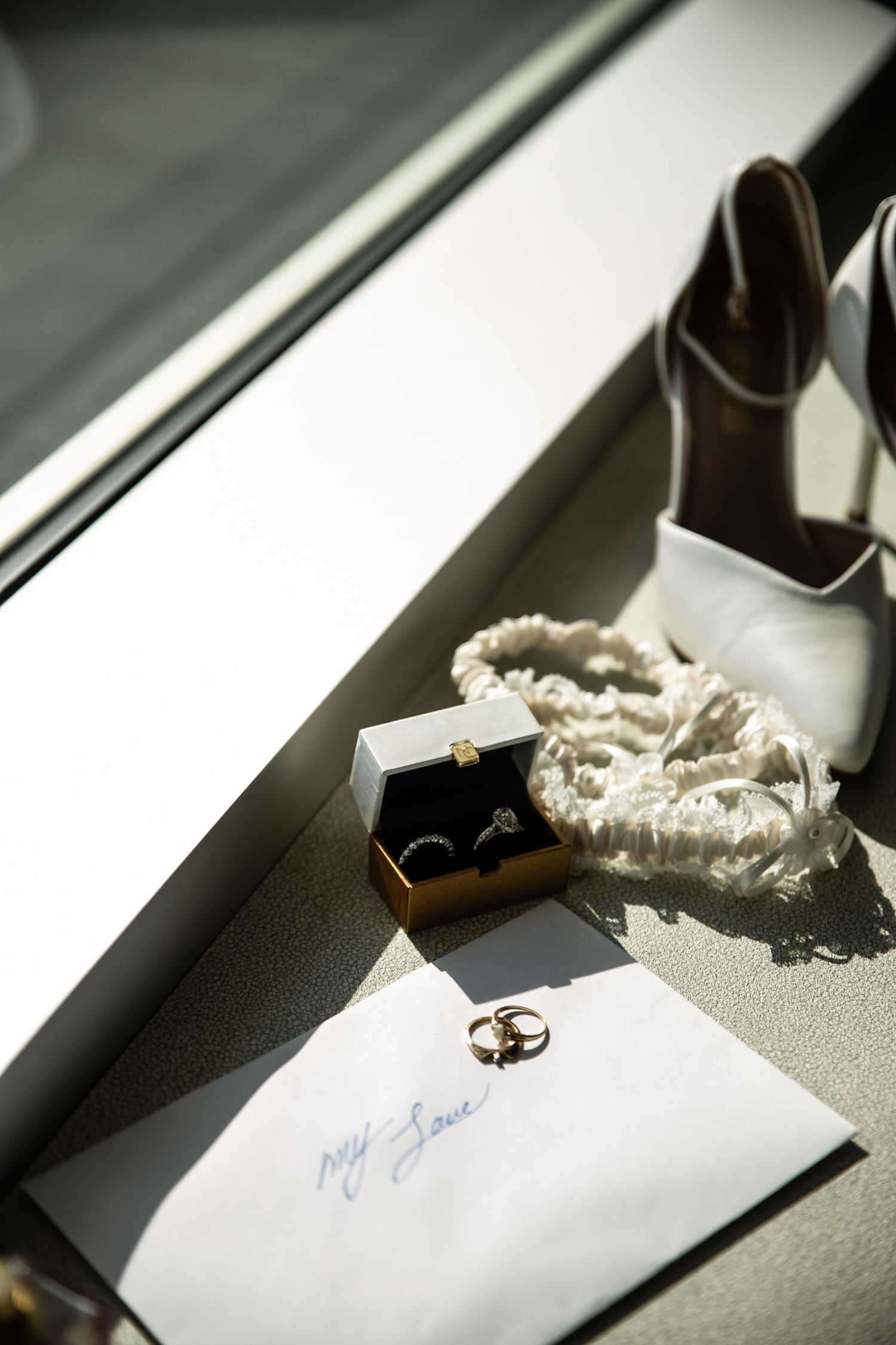 Wedding rings and details arranged artistically on a white surface in black and white.