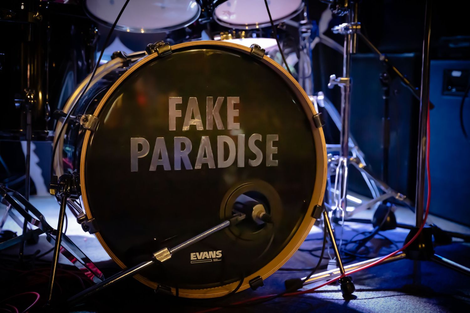 Drum kit on stage with text 'FAKE PARADISE' visible on bass drum head.