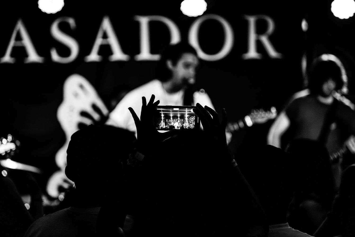 Dark concert stage with band silhouettes performing under dramatic lighting.