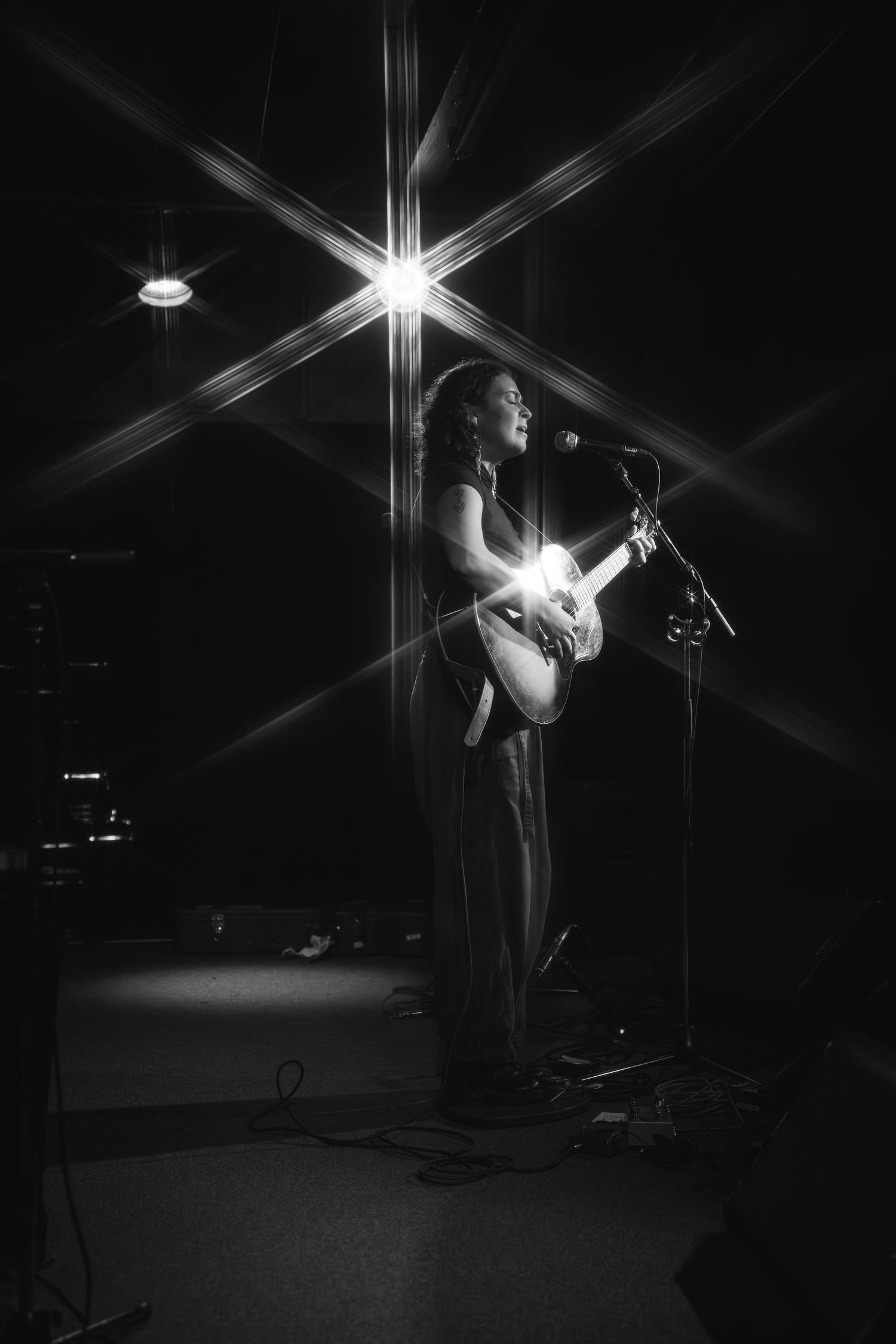 Musician performs with acoustic guitar under dramatic starburst lighting effect.