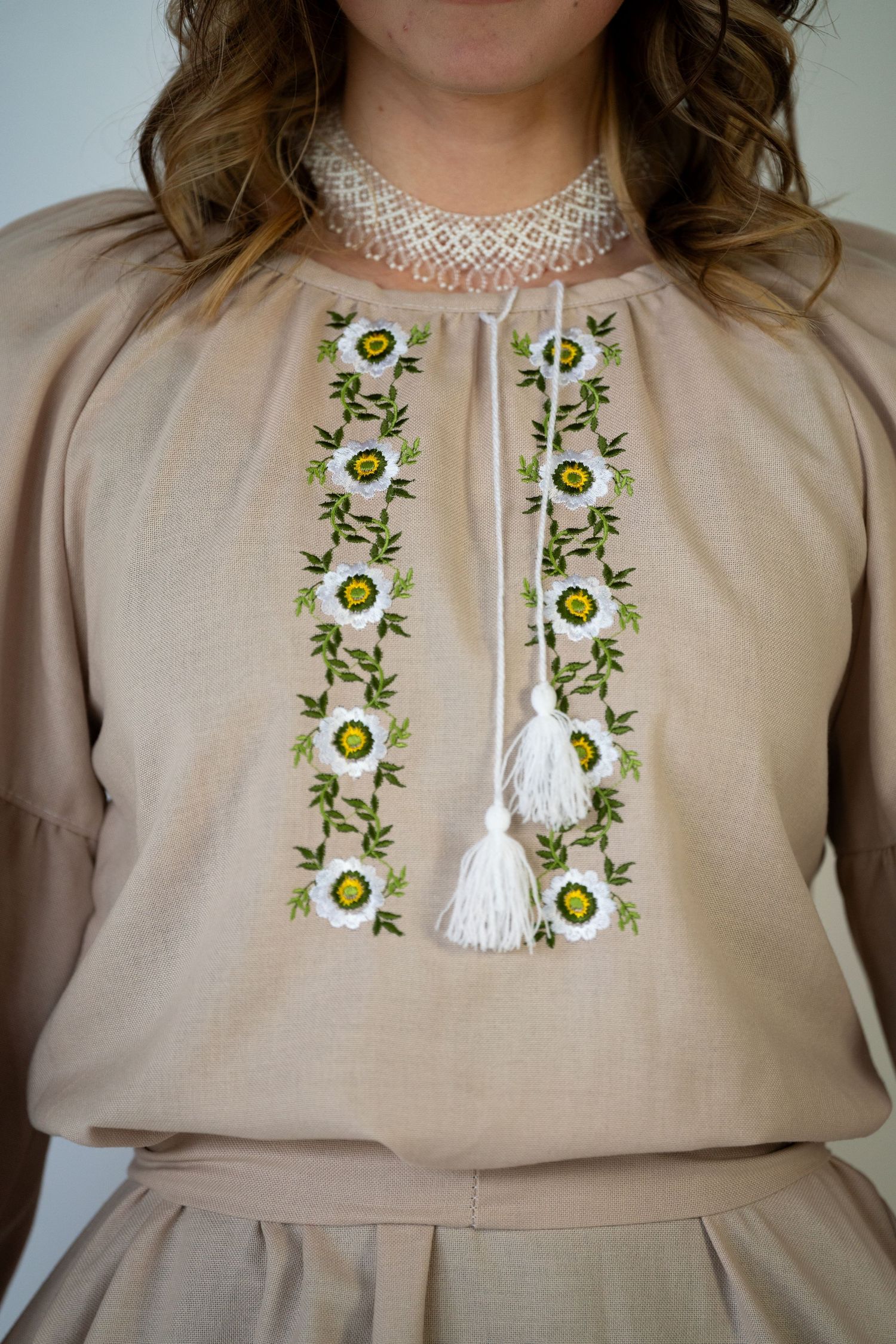 Beige dress with delicate green and white floral embroidery detail around the neckline.
