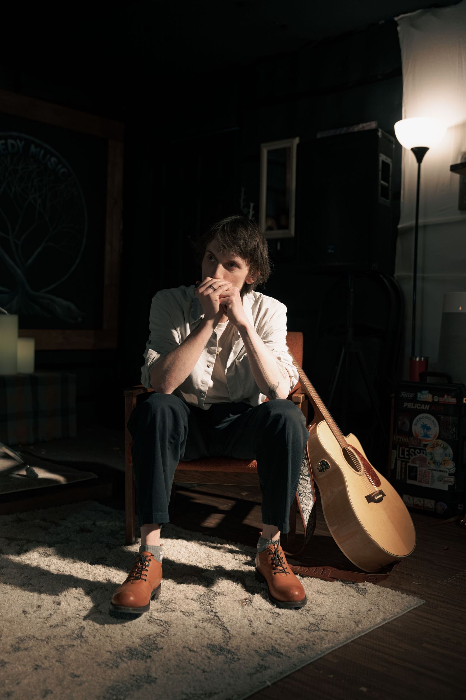 Dramatic series of photos showing acoustic guitar player in dark room with spotlight creating moody atmosphere.