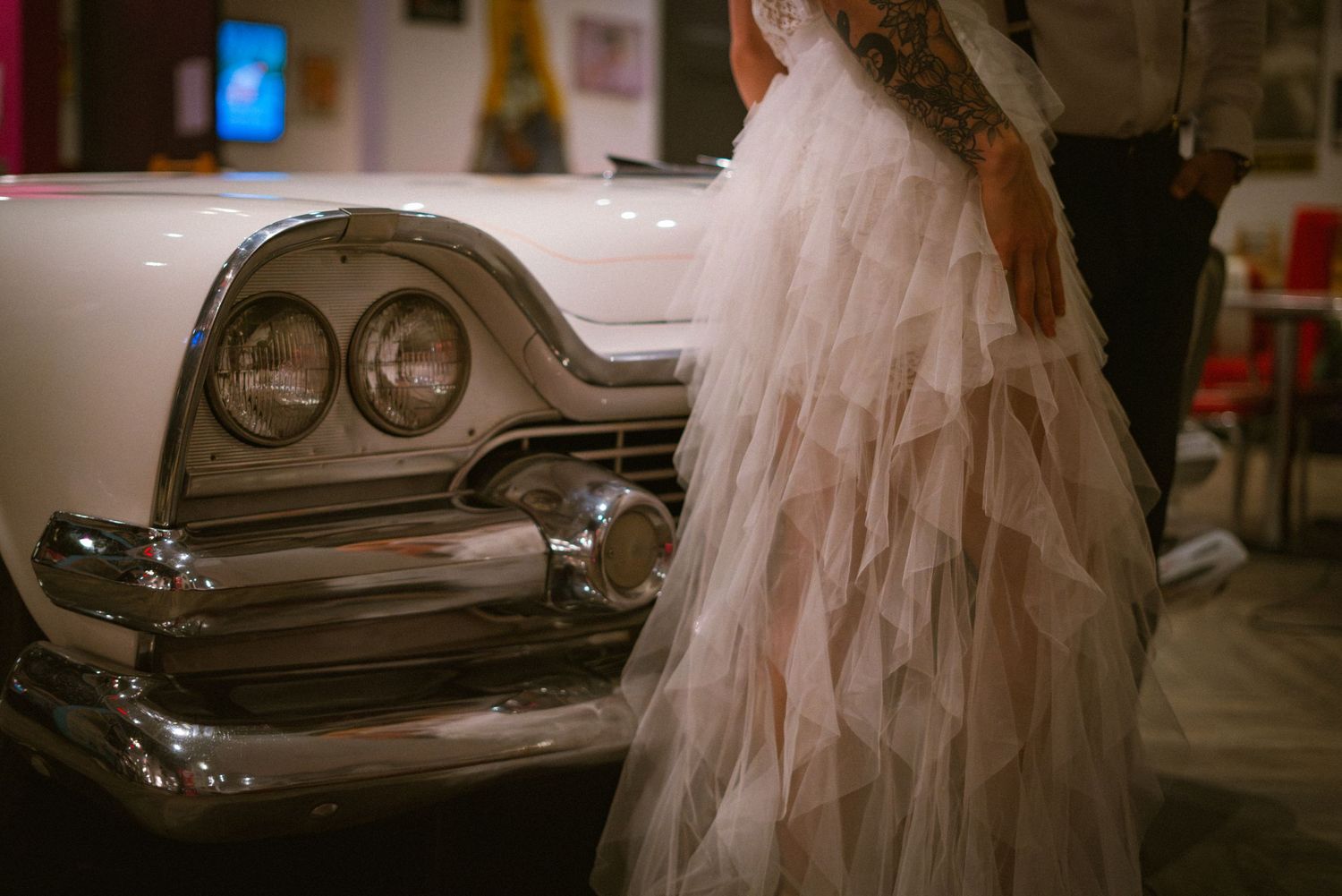 Artistic wedding photography featuring classic car and flowing white dress details.